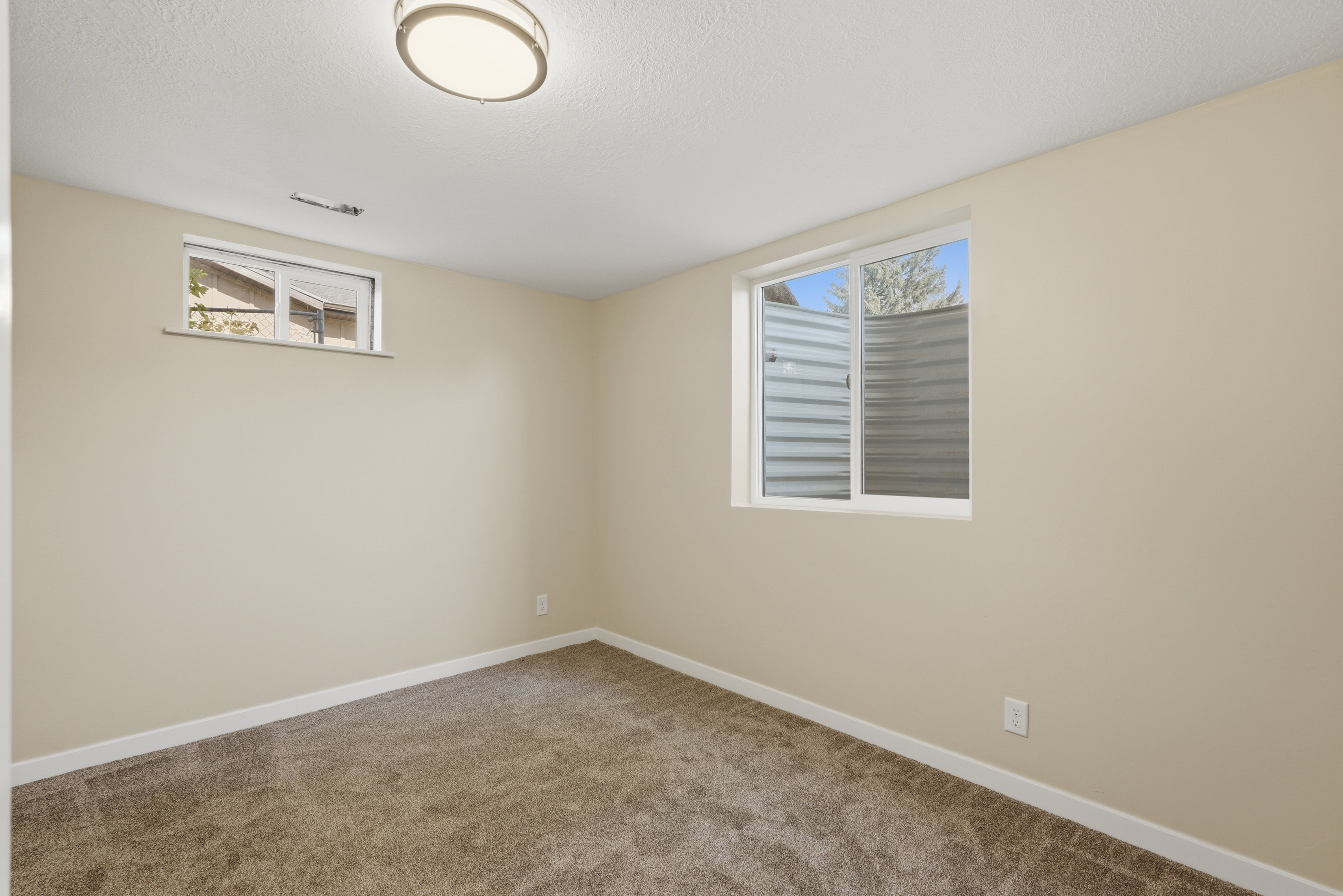 Neutral-toned room featuring plush carpet flooring and white baseboards