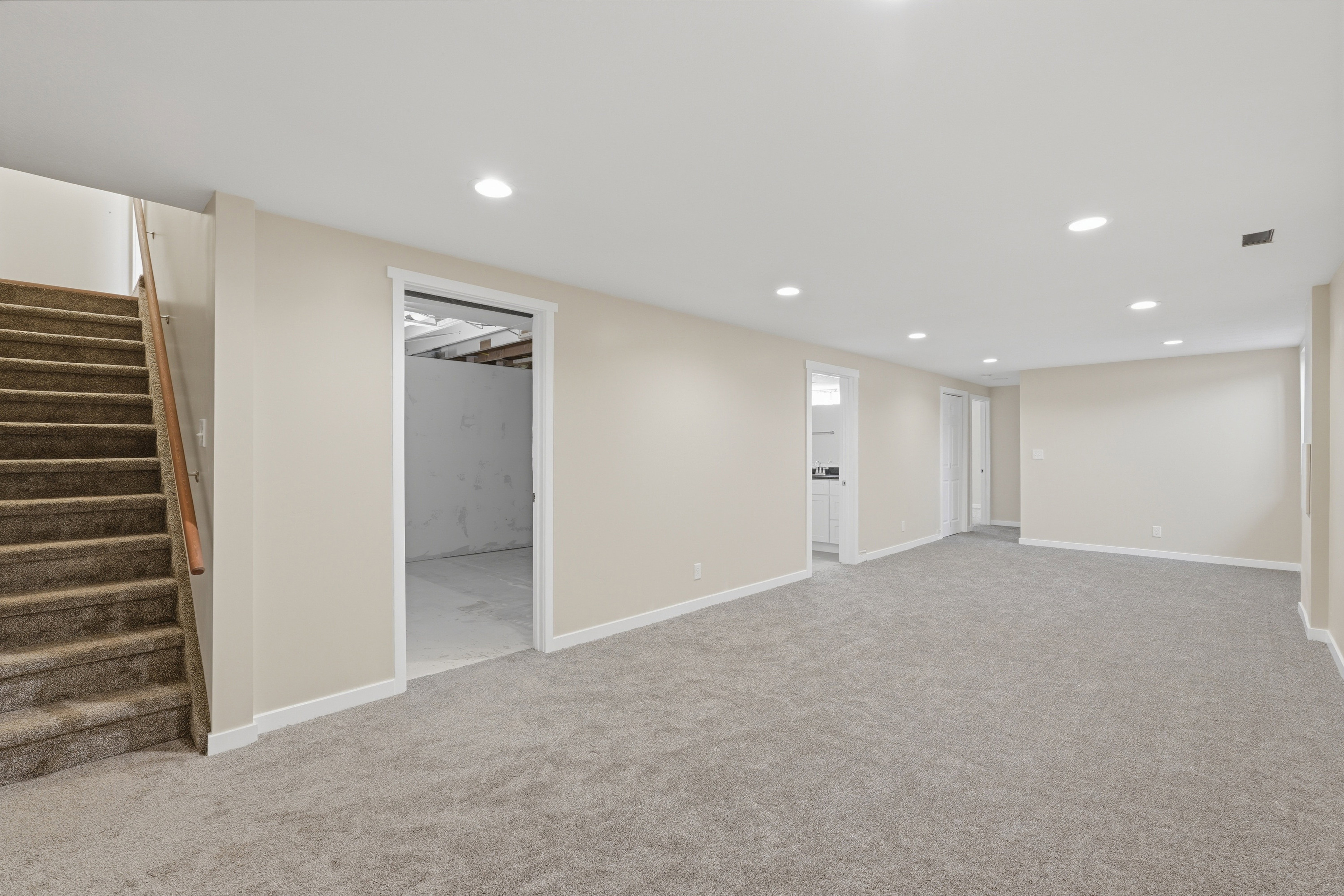 Spacious room featuring neutral carpeting, light-toned wall paint, recessed lighting, and white trim