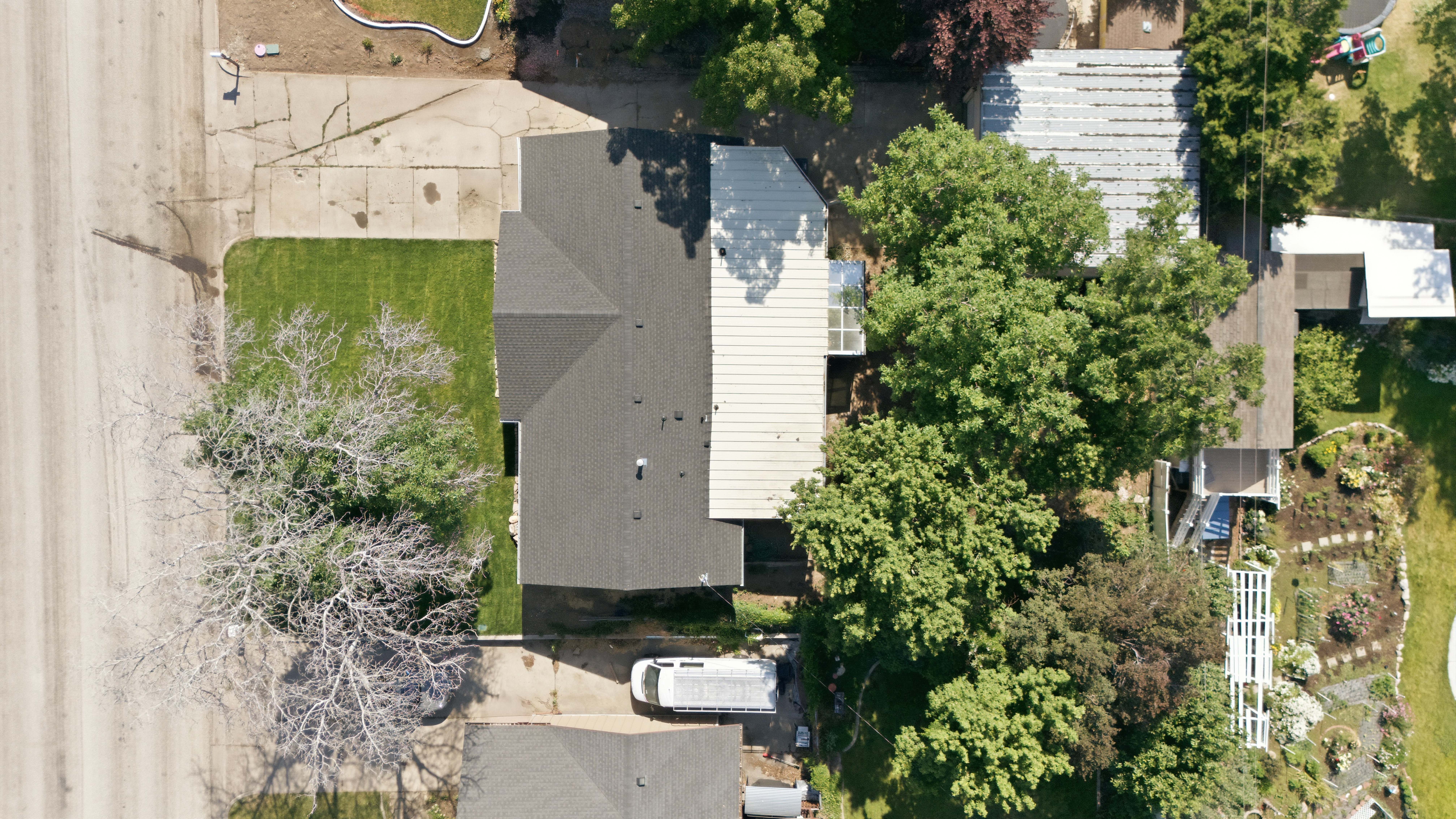 Property featuring a dark shingle roof, green lawn, and mature trees