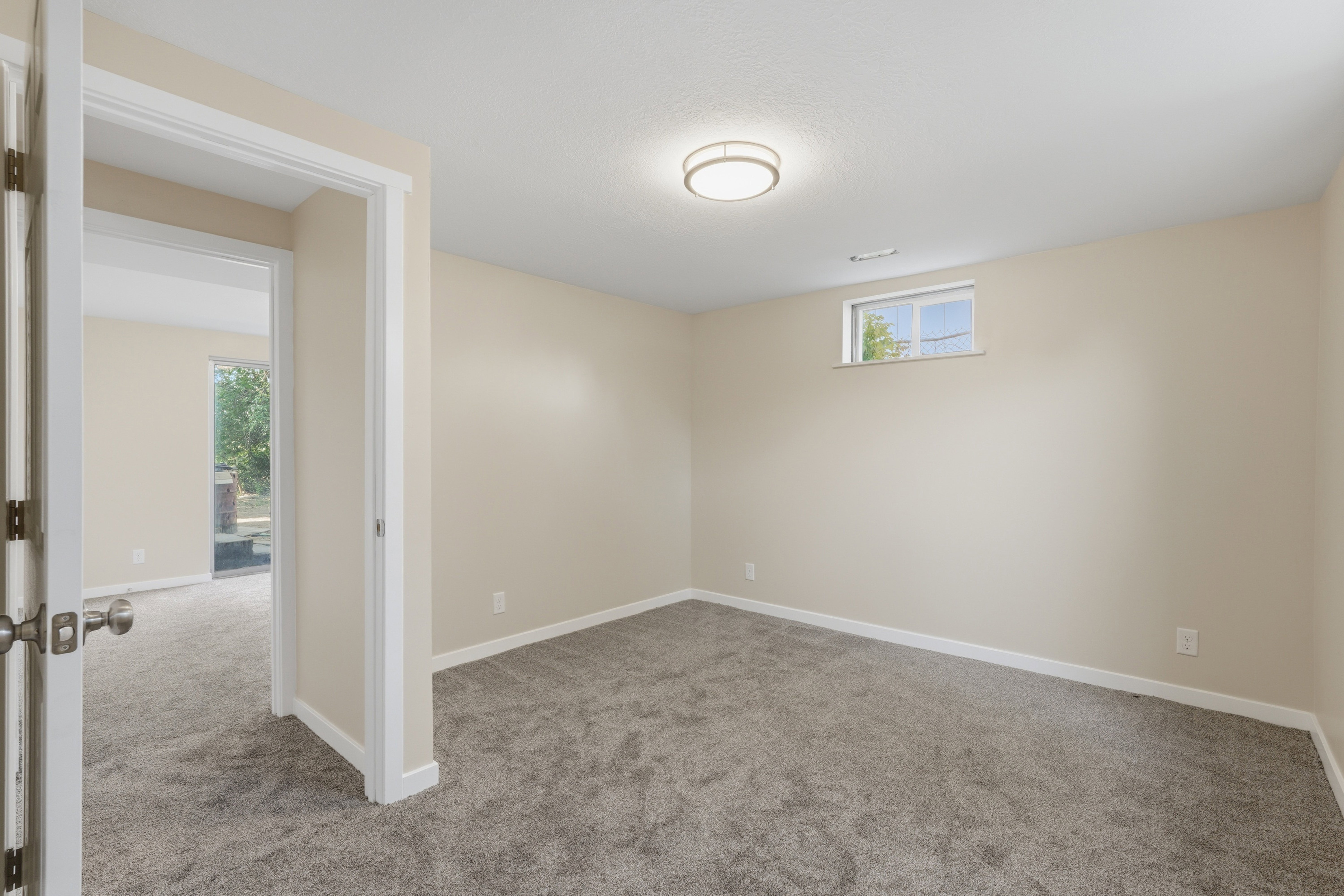 Spacious room featuring neutral paint, gray carpeting, white trim, a flush-mount ceiling light, and a high window