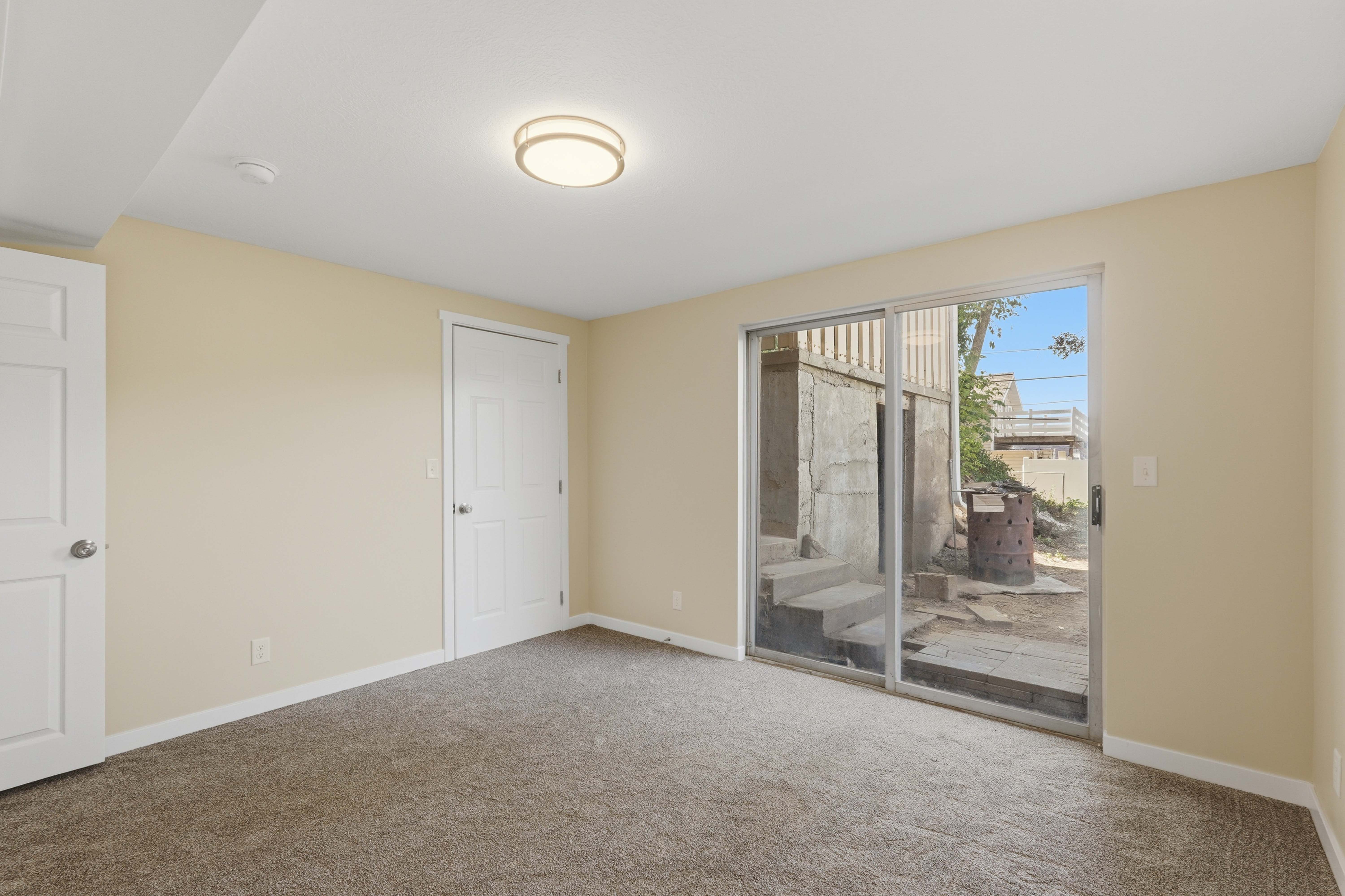 Carpeted room featuring a ceiling-mounted light fixture and sliding glass door