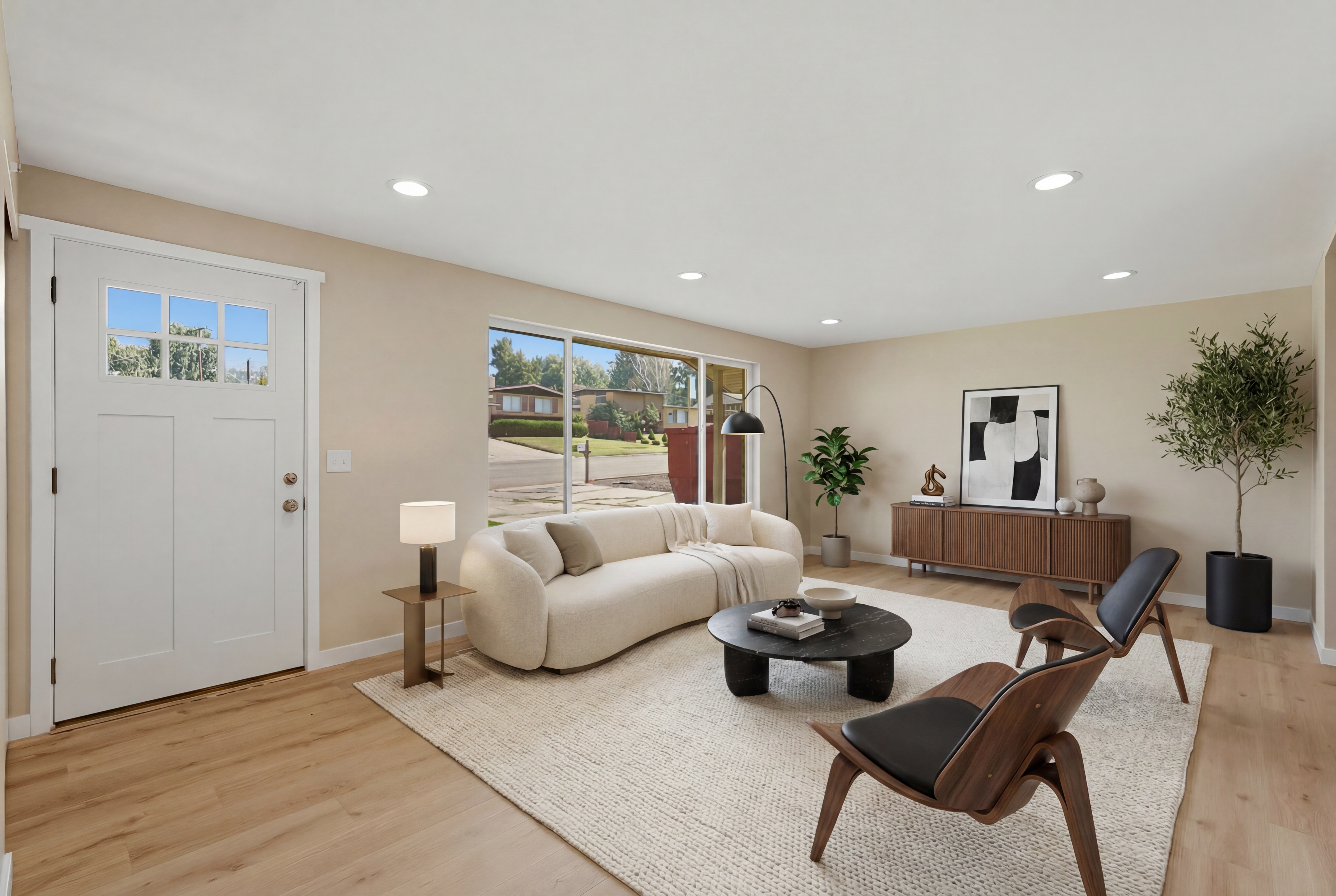 Spacious living area featuring light wood-finish flooring, recessed lighting, and a prominent picture window. Virtually Staged