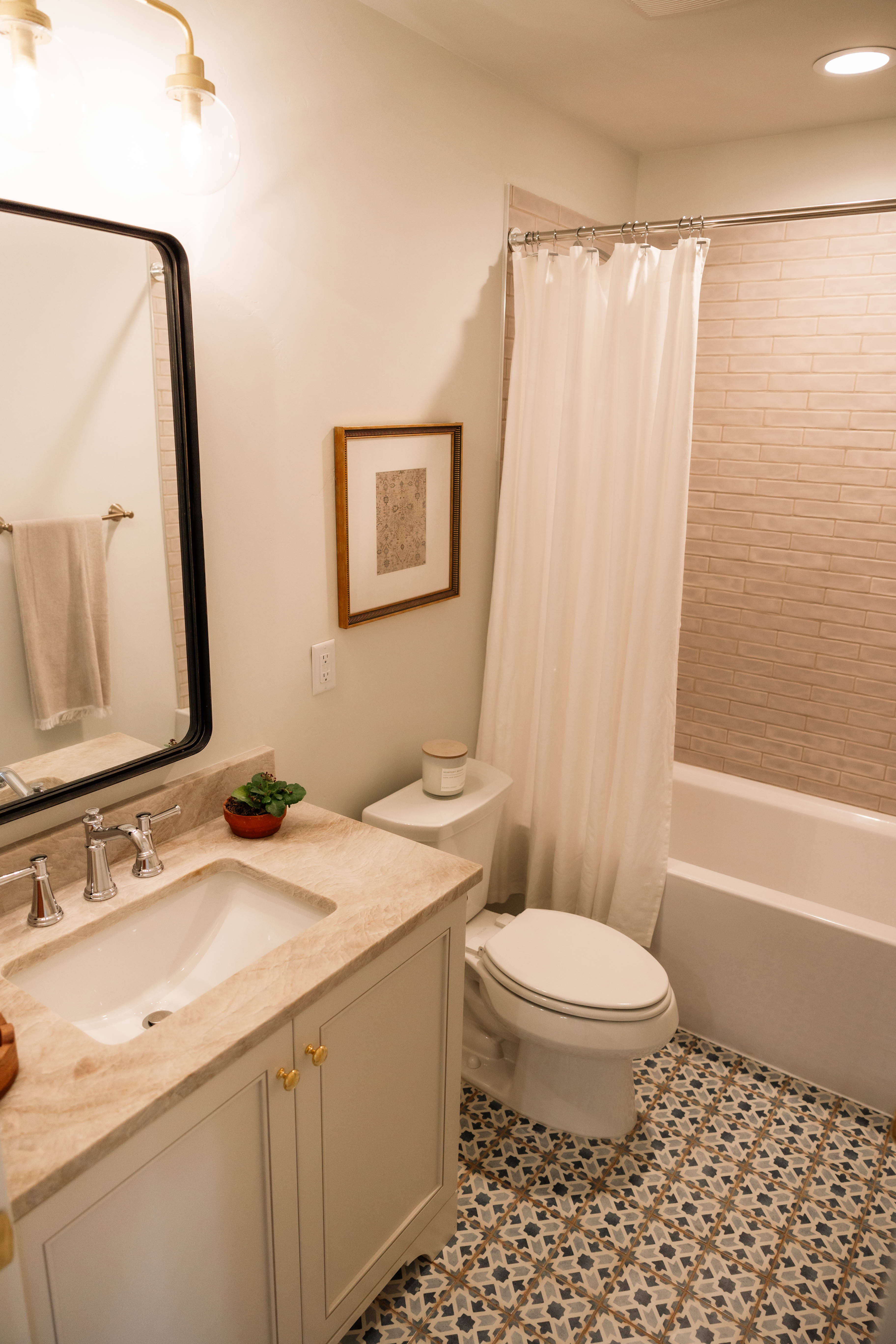 Bathroom featuring a patterned tile floor, a single vanity with a light-colored countertop, and a built-in bathtub with a tiled surround