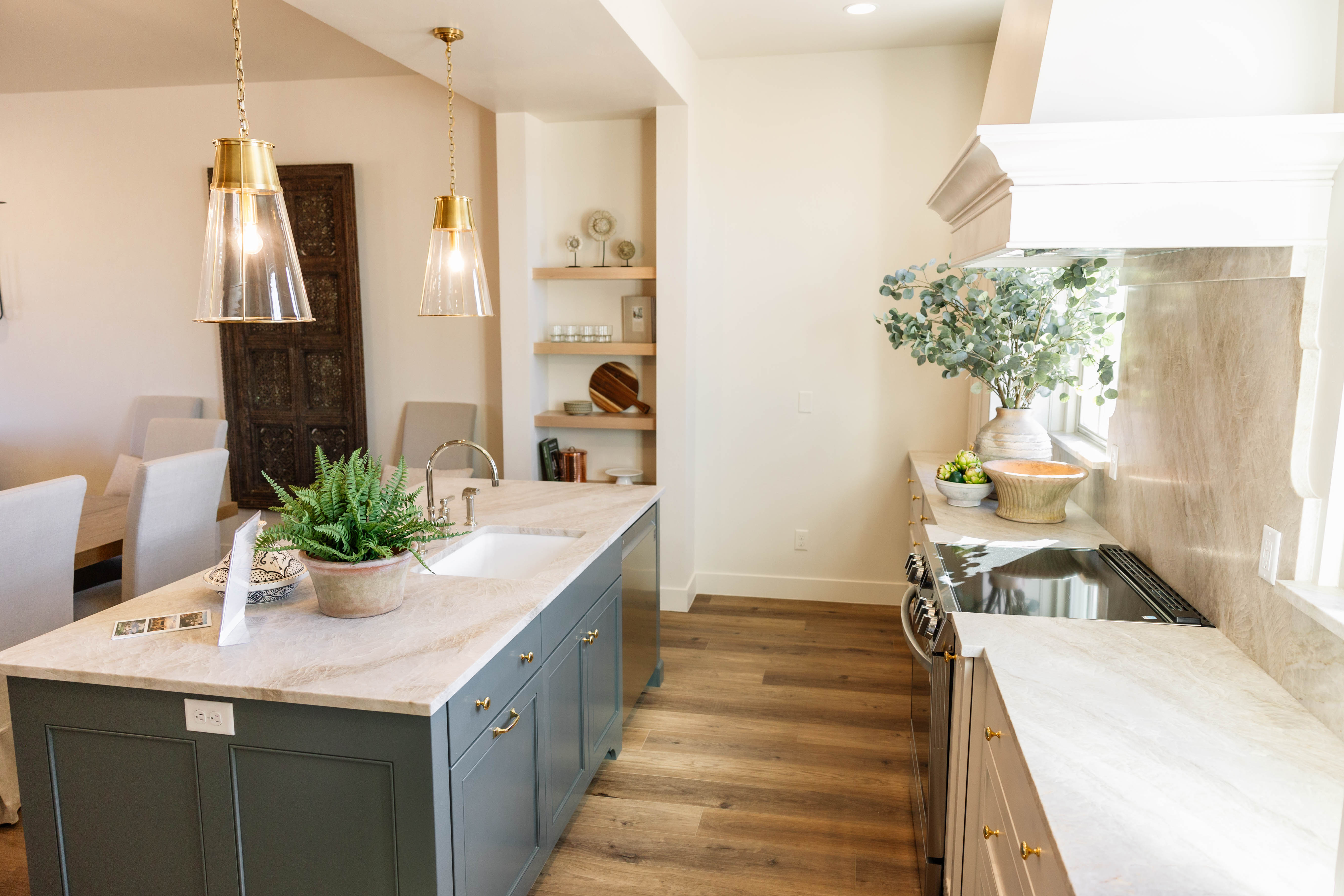 Gourmet kitchen featuring a spacious island with integrated sink, stone countertops, and wood-finish flooring