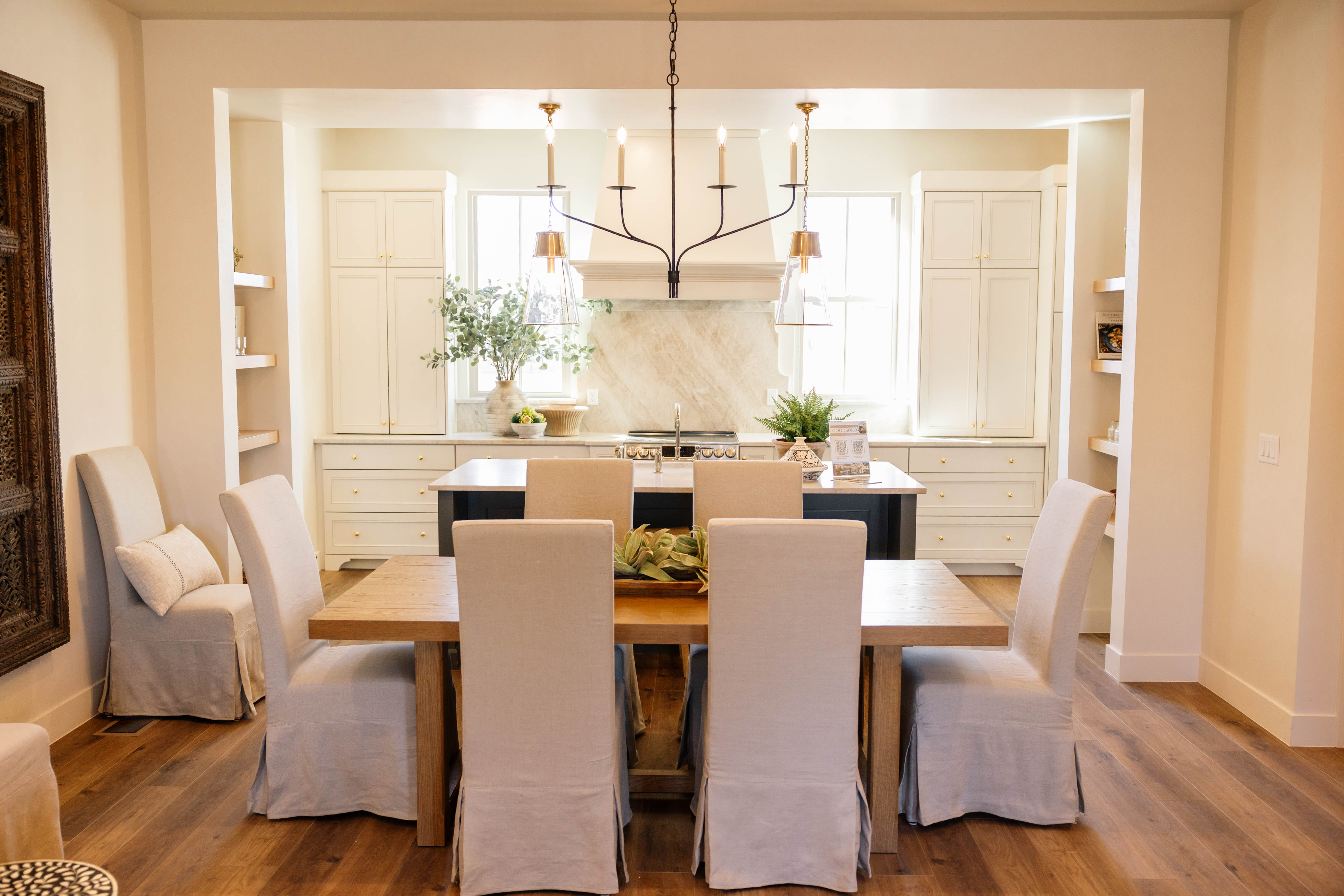 Open-concept dining area featuring wood-finish flooring, a rectangular wood dining table, and a black chandelier with candelabra-style lights