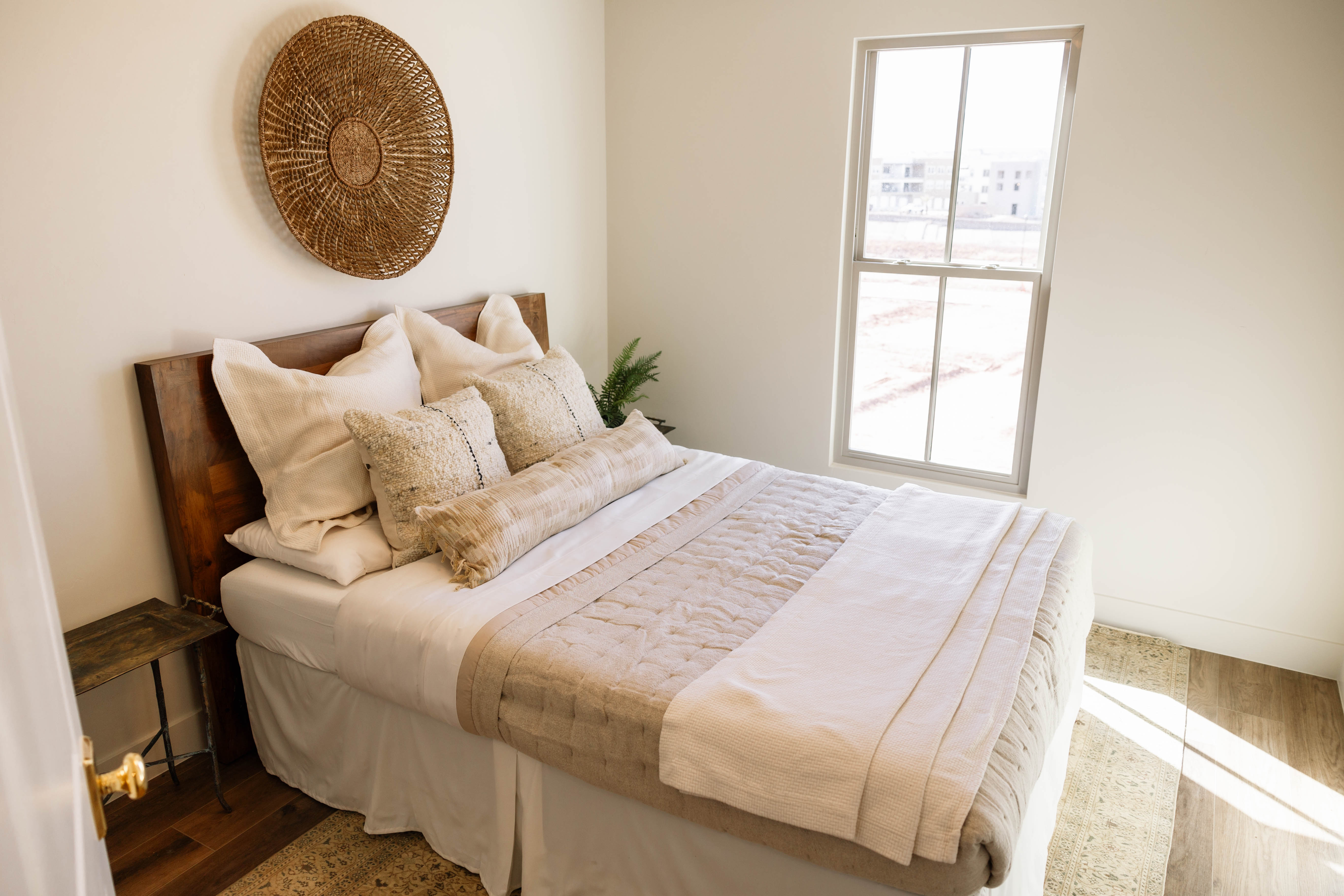 Bright room featuring a single window, a dark wood-finish headboard, light-toned walls, and wood-finish flooring
