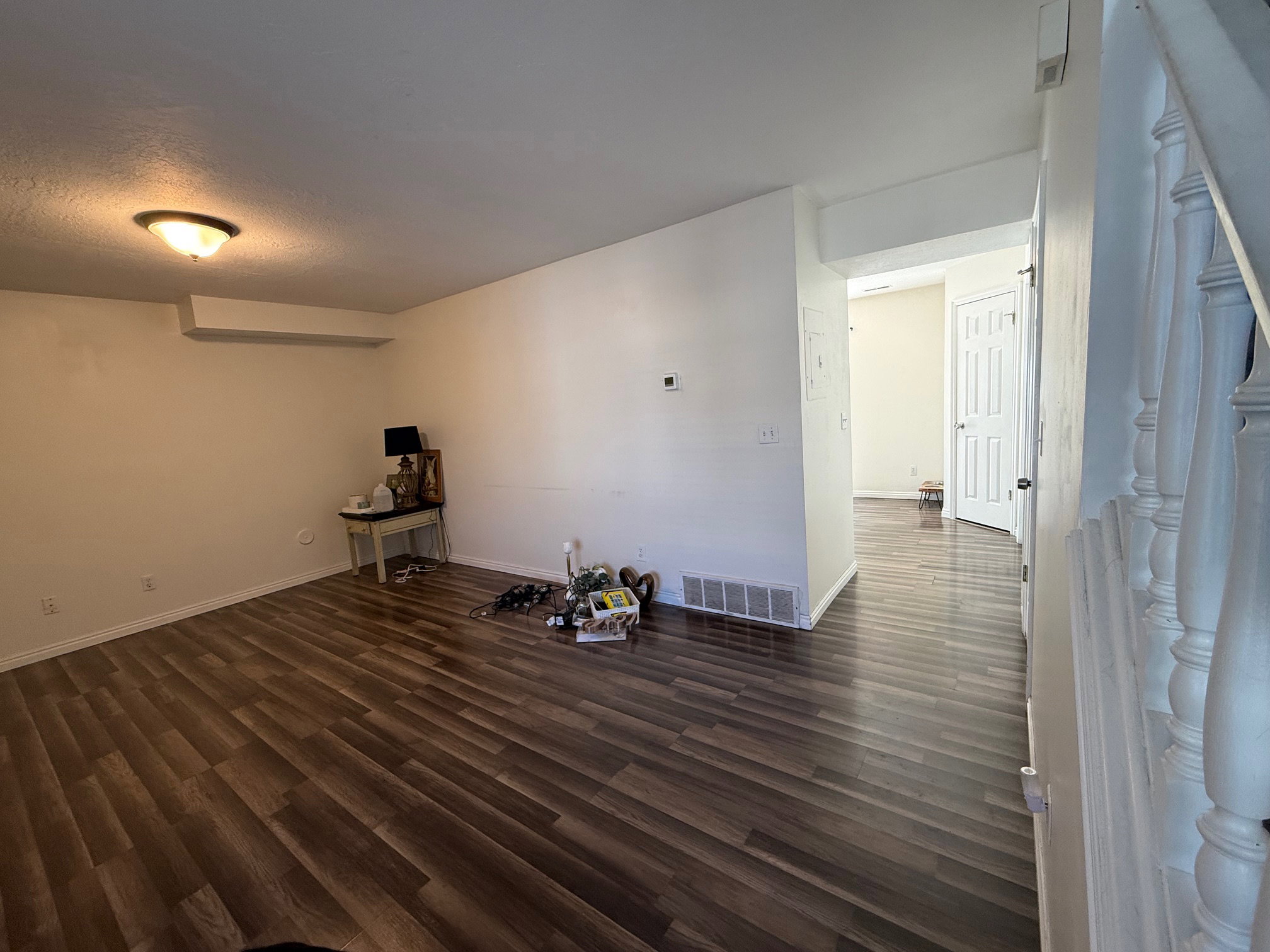 Spacious room with wood-finish flooring, white baseboards, and neutral wall tones