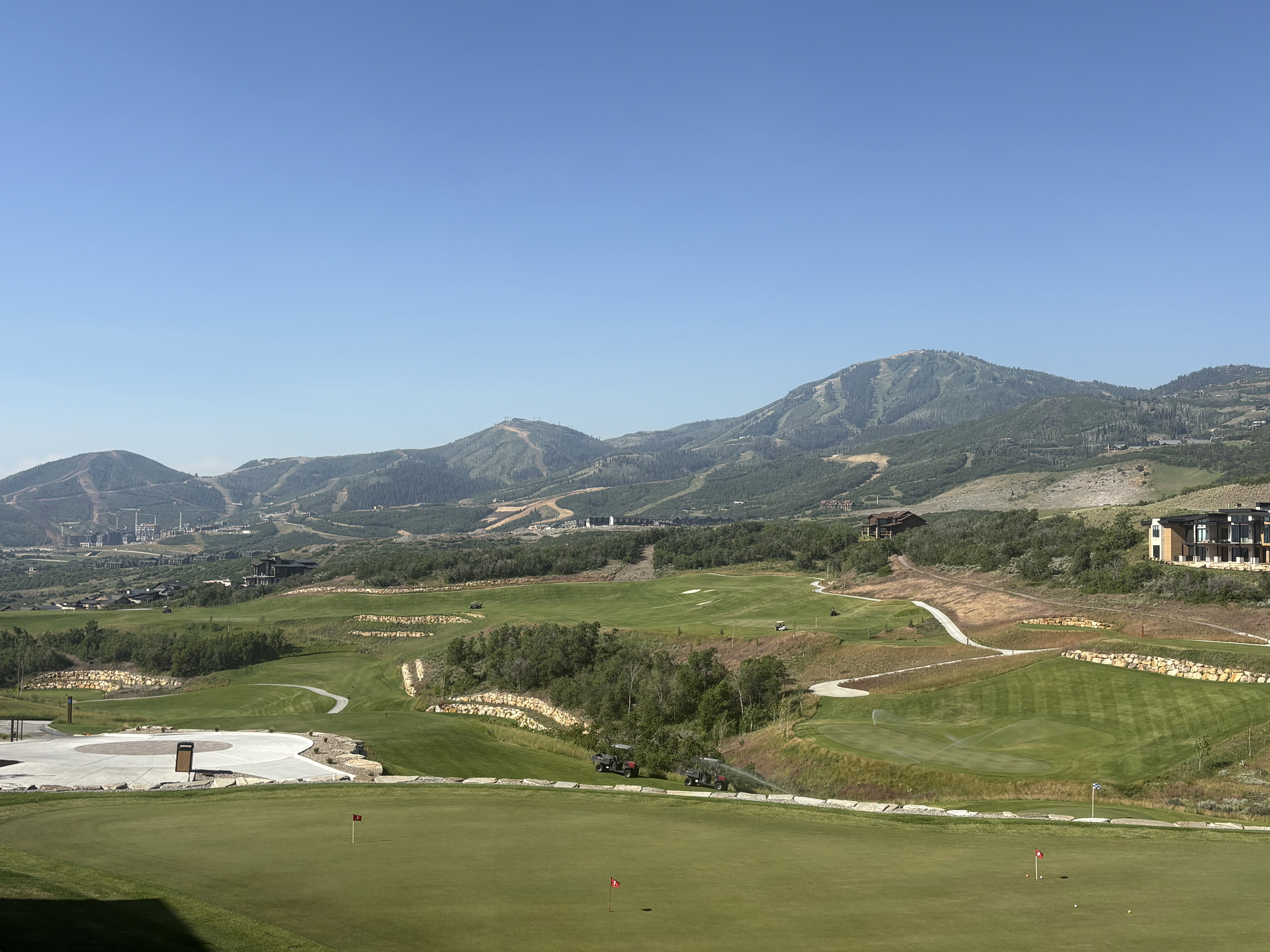 Expansive golf course setting featuring manicured greens and surrounding mountainous terrain