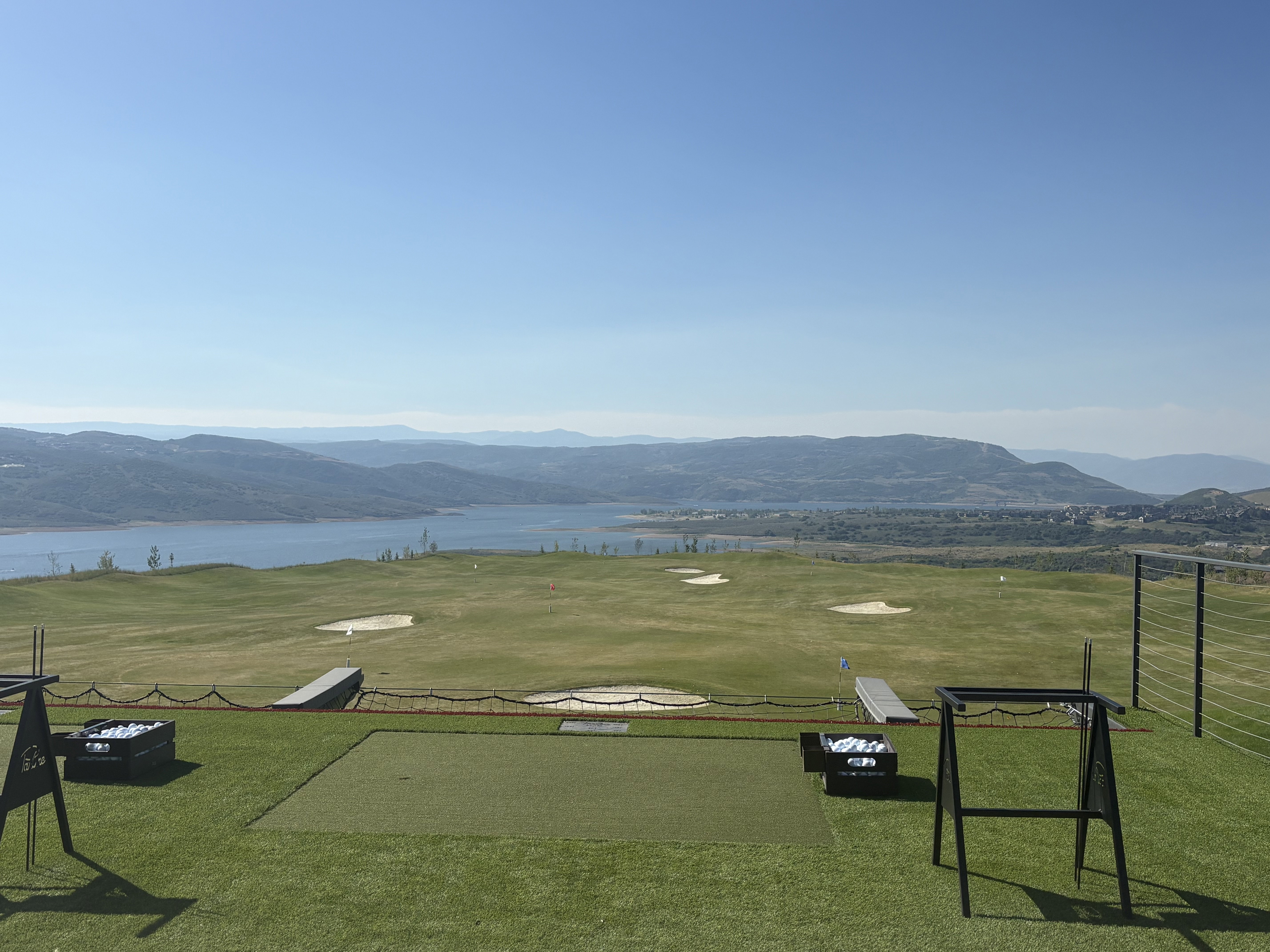 Golf course practice area featuring artificial turf tee boxes and a putting green