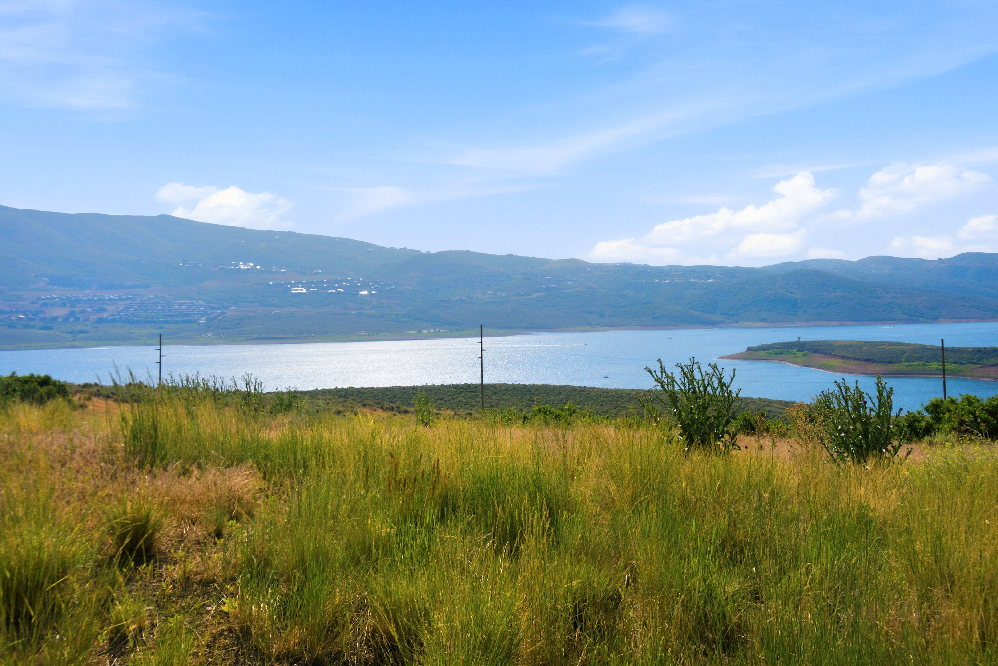 Expansive natural landscape featuring a prominent body of water, distant mountain range, and a clear blue sky