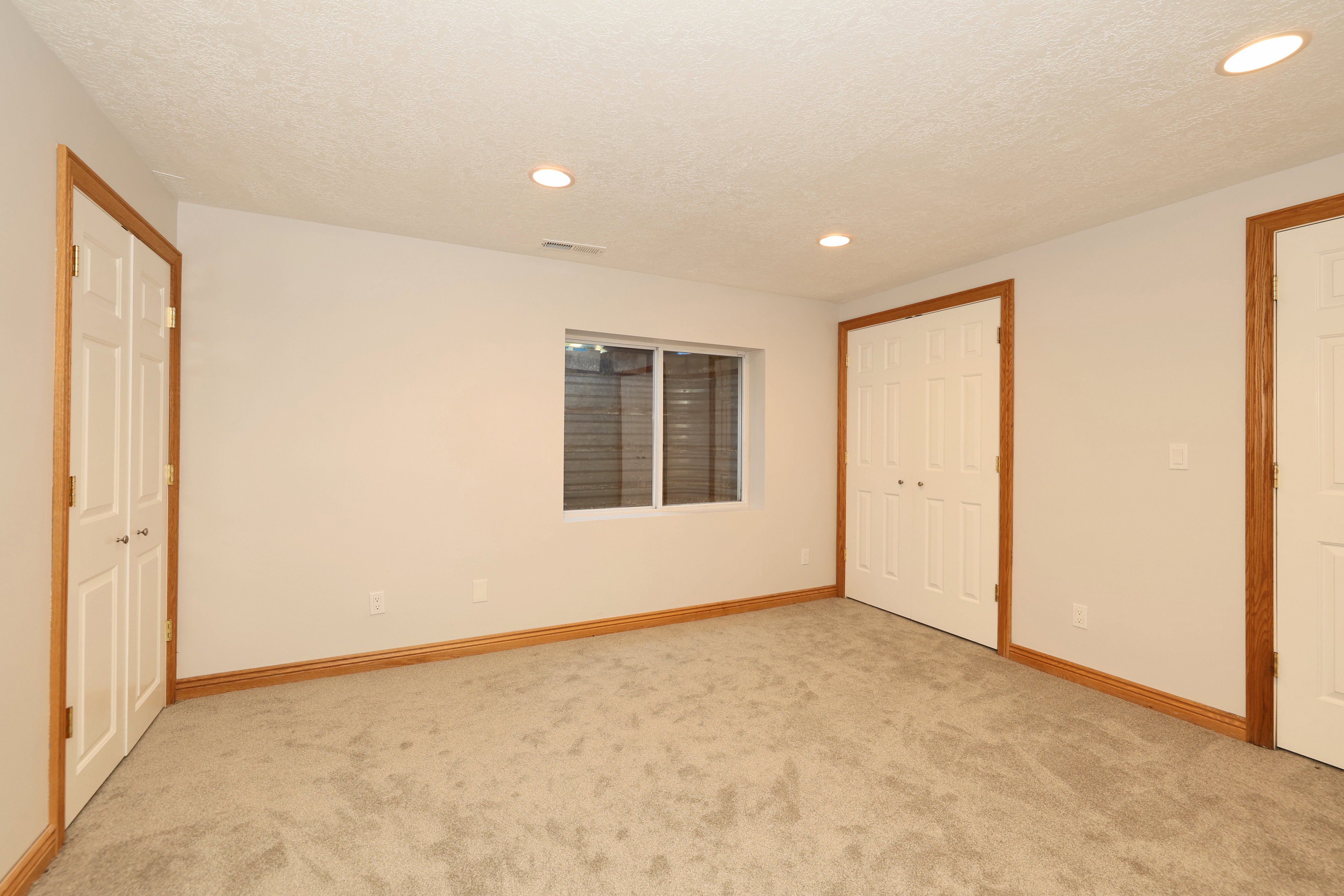 Carpeted room featuring white walls, wood trim, recessed lighting, and a window with blinds