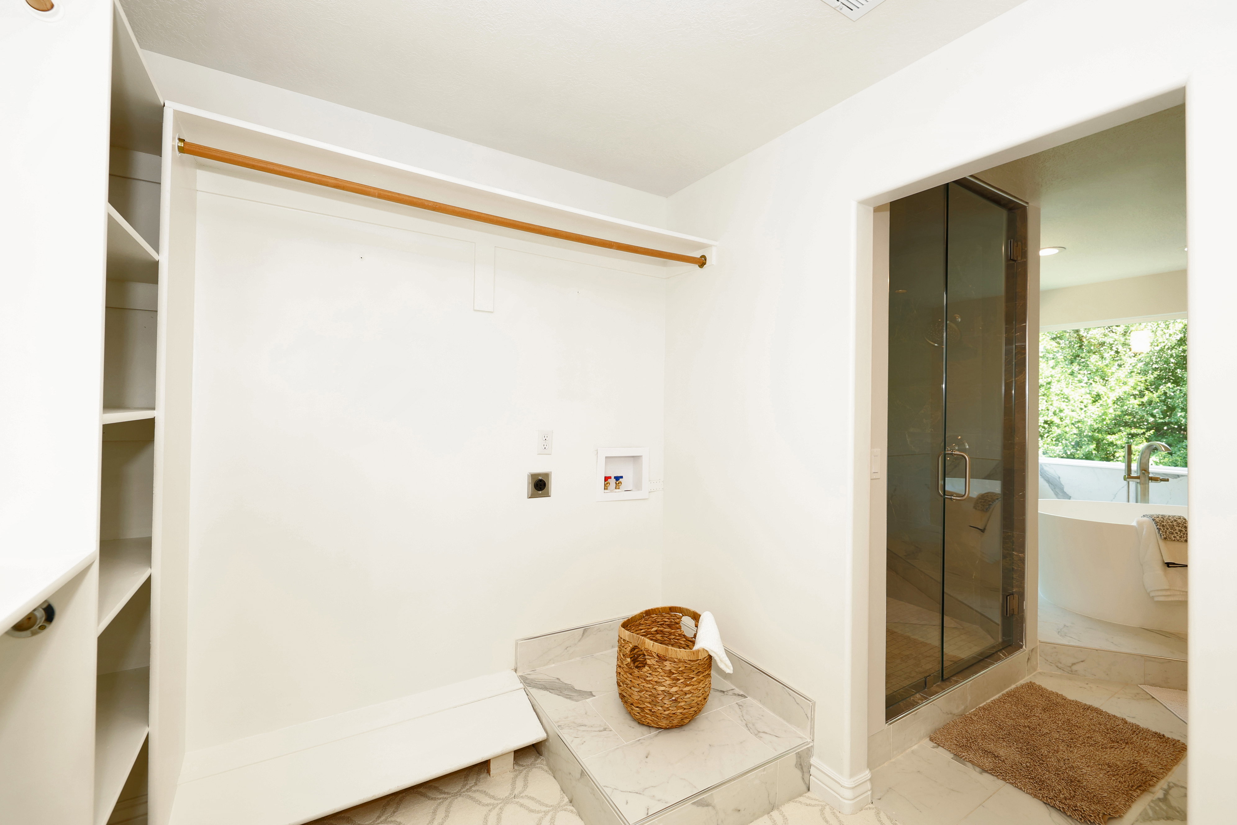 Integrated laundry area featuring plumbing connections for a washer and dryer, adjacent to a custom walk-in closet with built-in shelving and a clothing rod