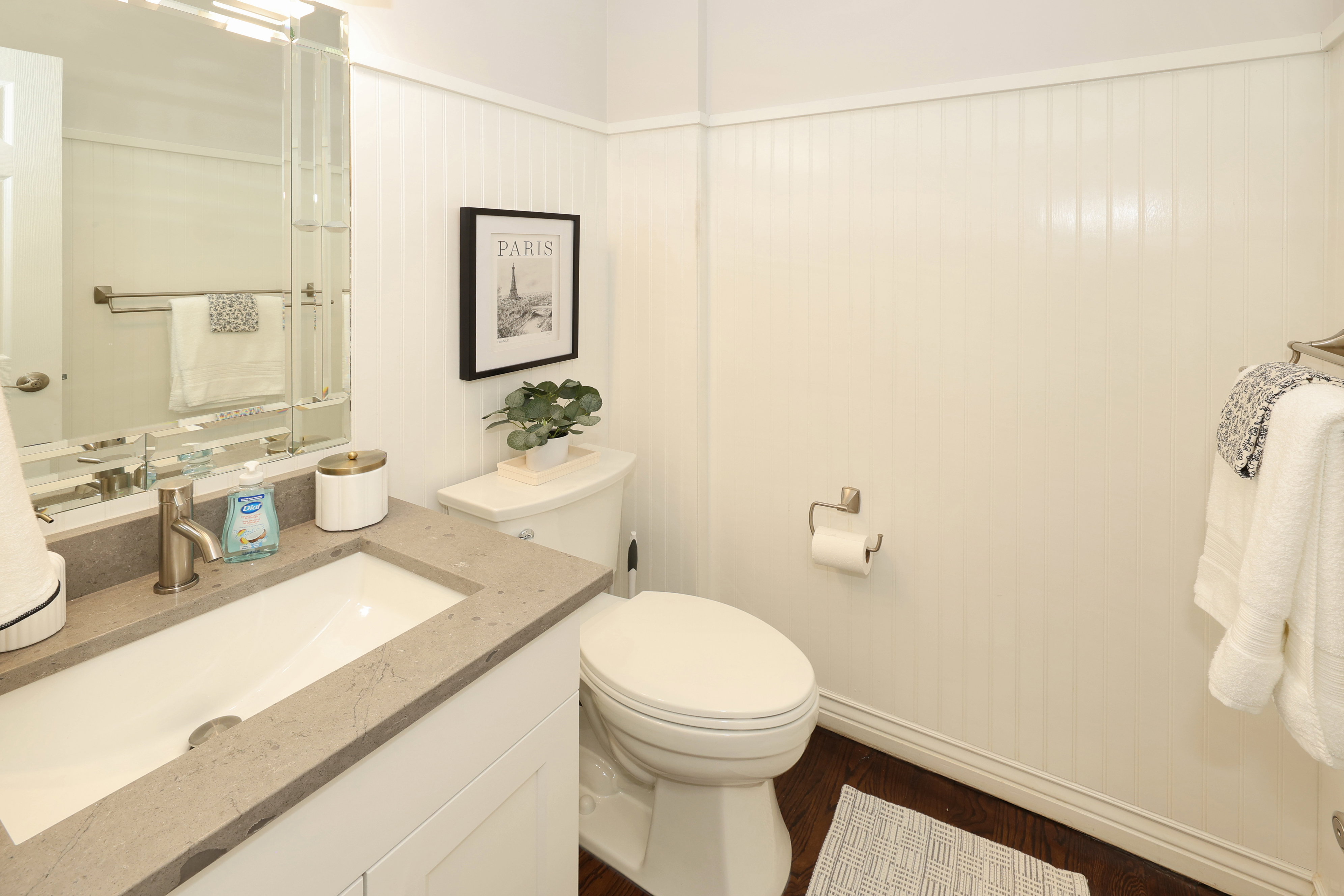 Bathroom featuring a single vanity with a rectangular basin, light-toned stone countertop, and brushed nickel faucet