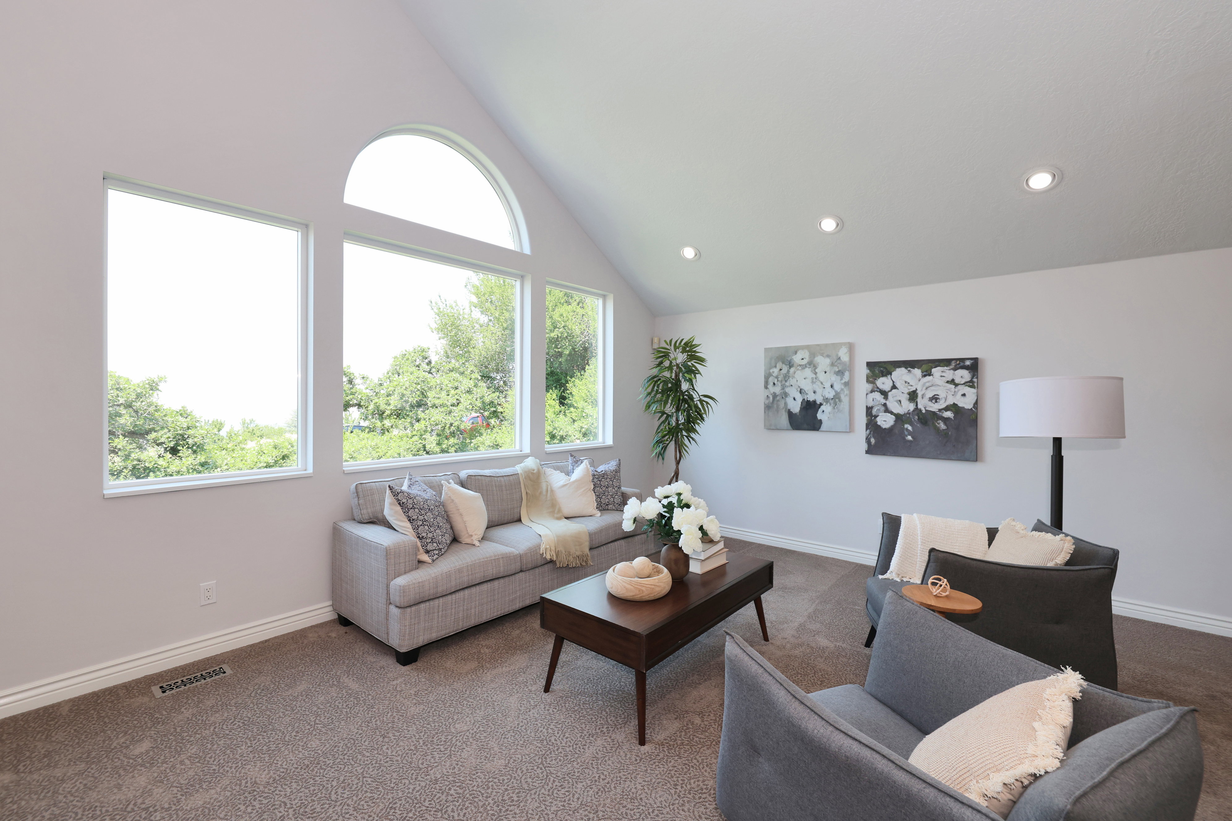 Vaulted ceiling living space featuring a wall of windows including an arch-top window, recessed lighting, and soft carpet flooring