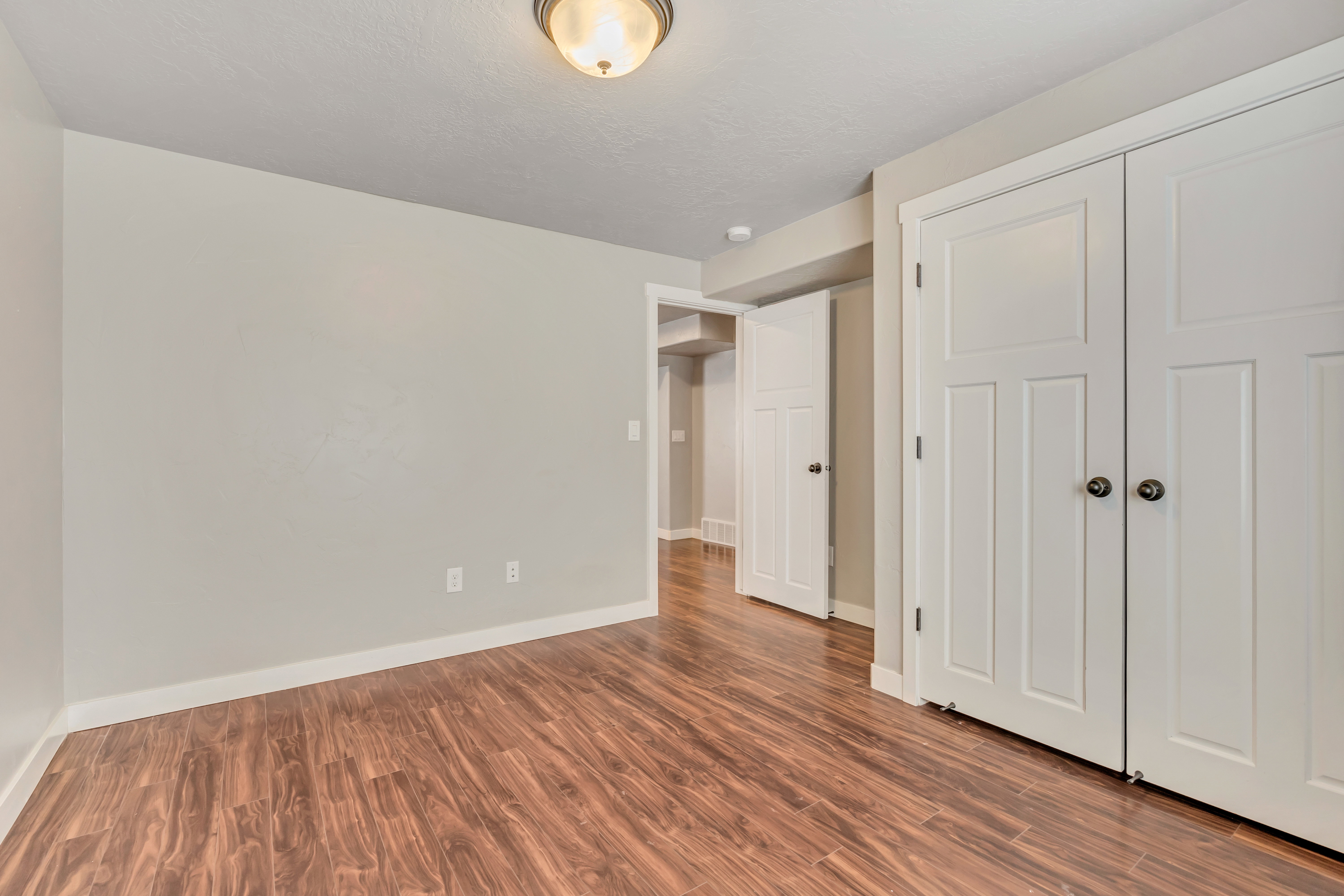 Room featuring wood-finish flooring, light neutral wall tones, and white trim