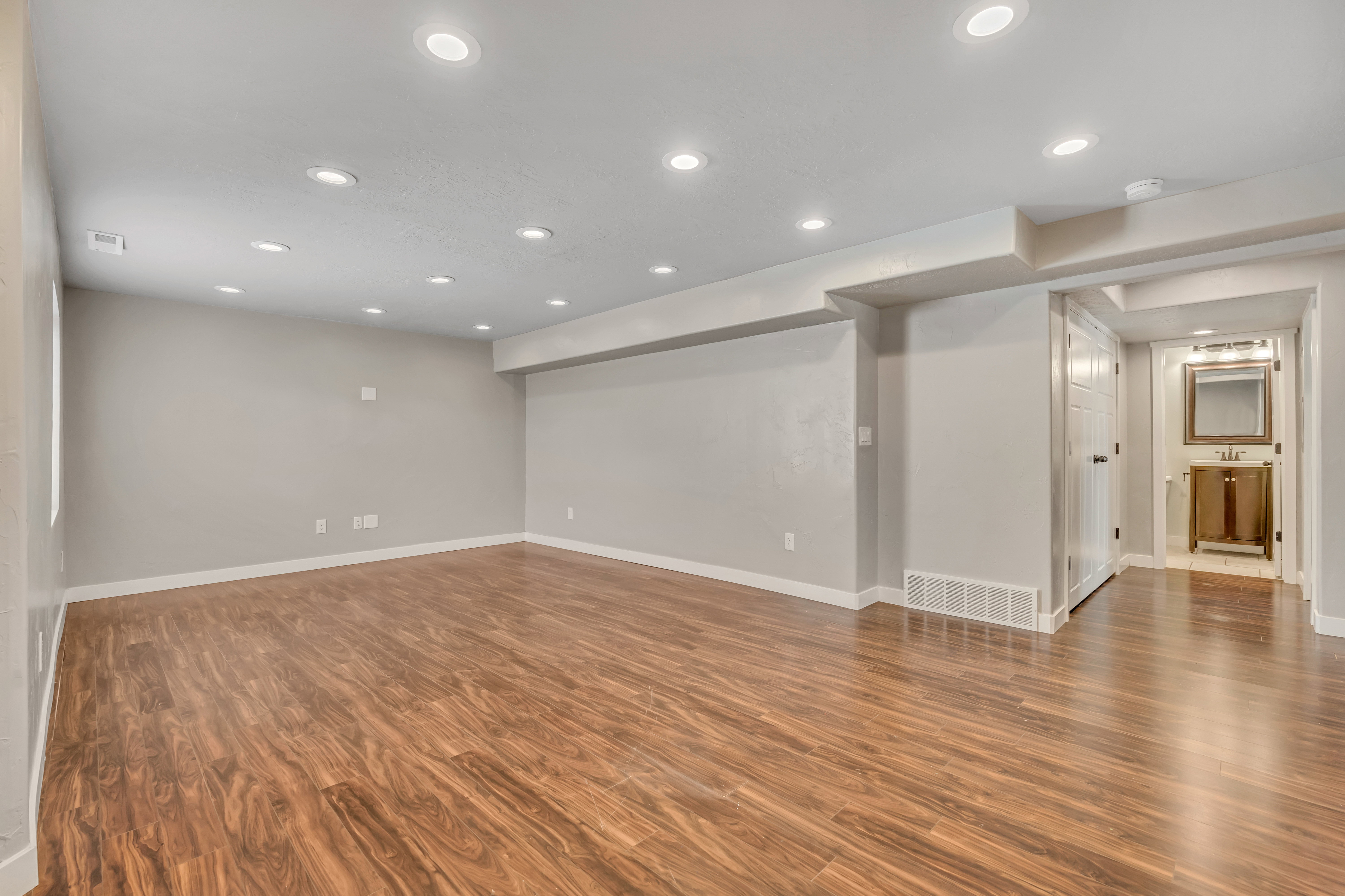 Spacious room featuring wood-finish flooring, recessed lighting, neutral wall paint, and white baseboards