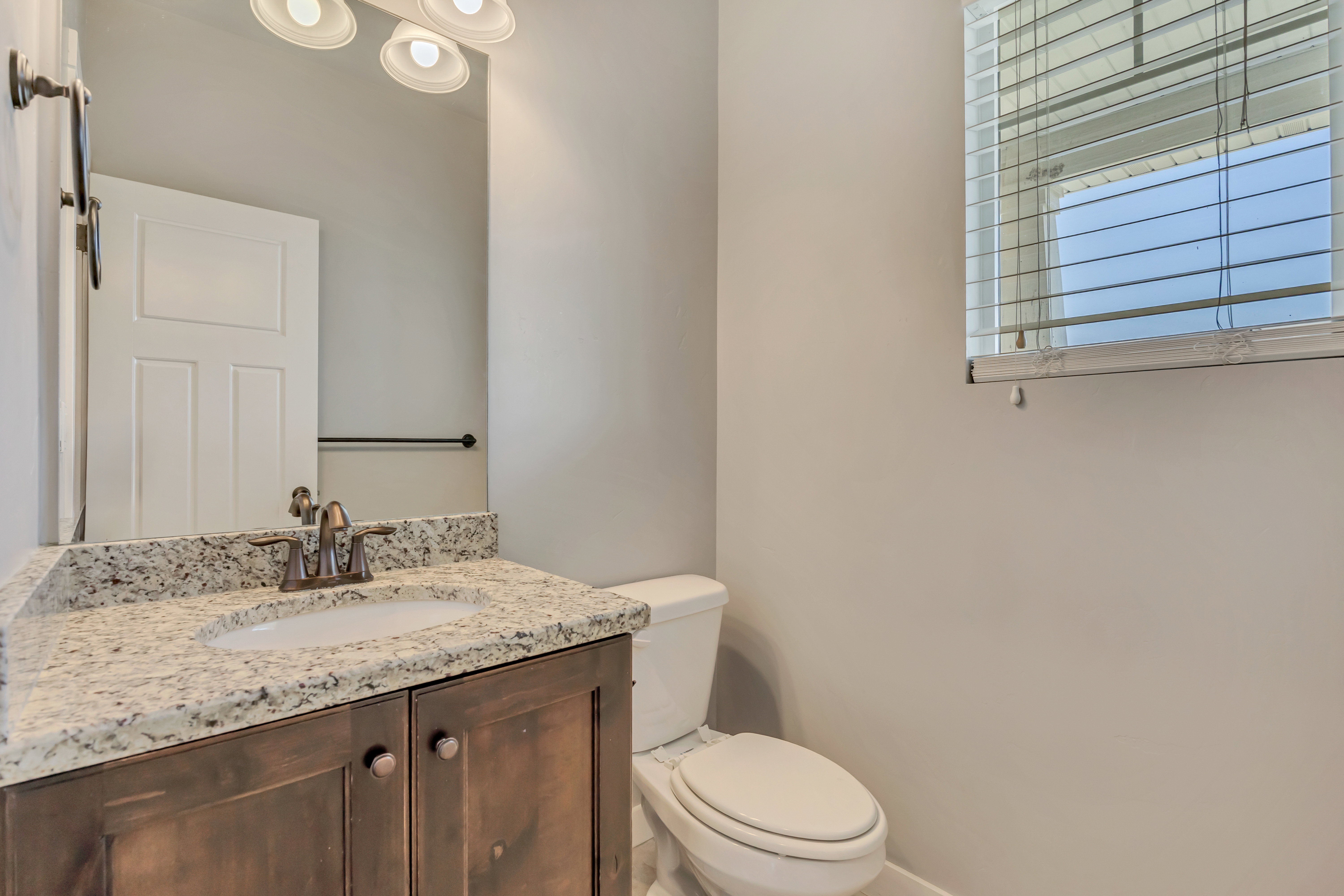 Bathroom vanity featuring a speckled countertop, integrated sink, and dark wood cabinetry