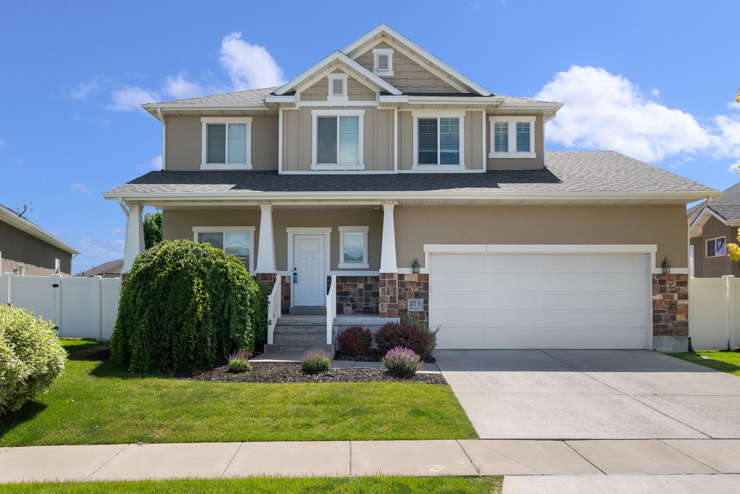Two-story home with a two-car garage, covered entry, and stone facade accents