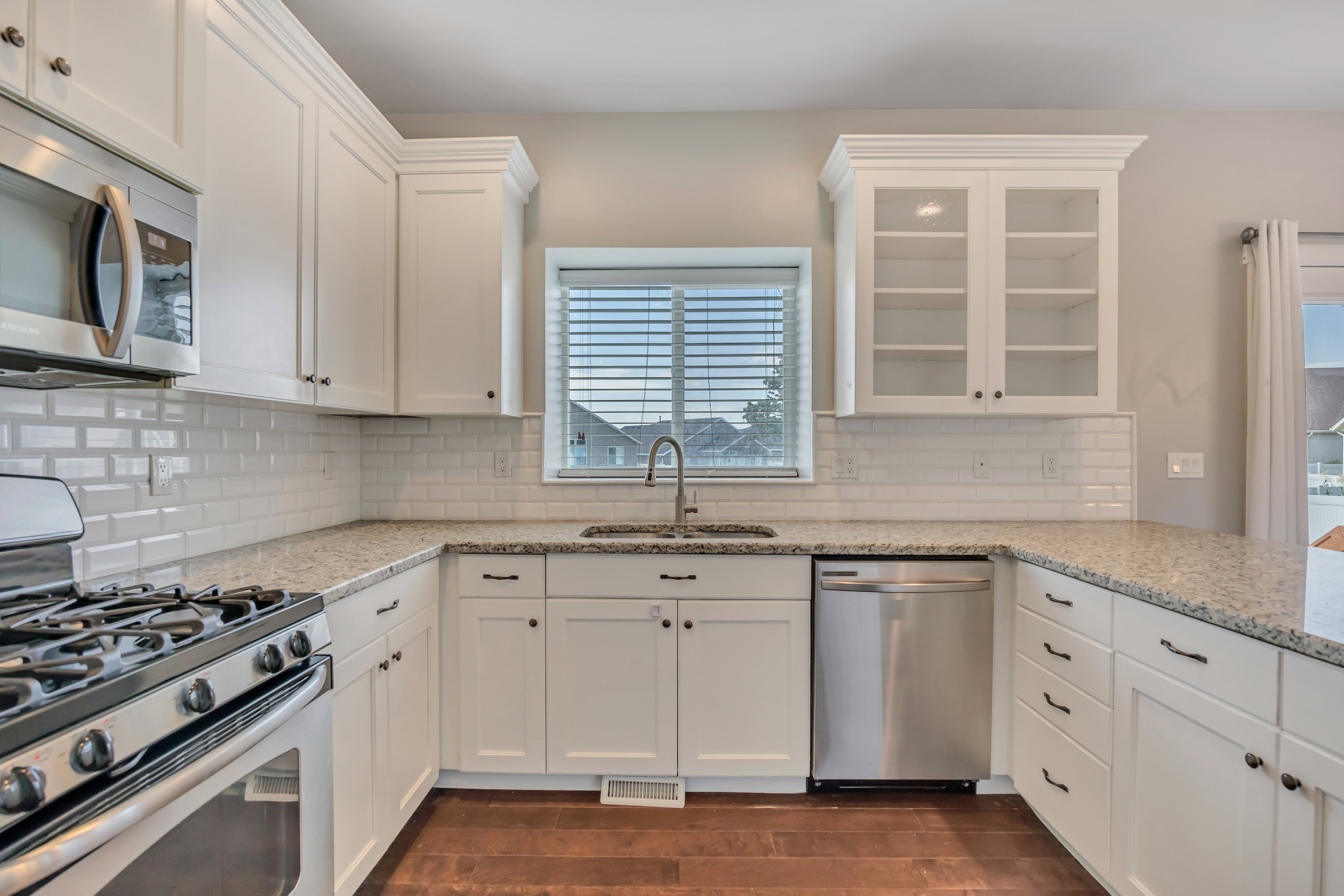 U-shaped kitchen featuring white cabinetry, light-toned countertops, and wood-finish flooring