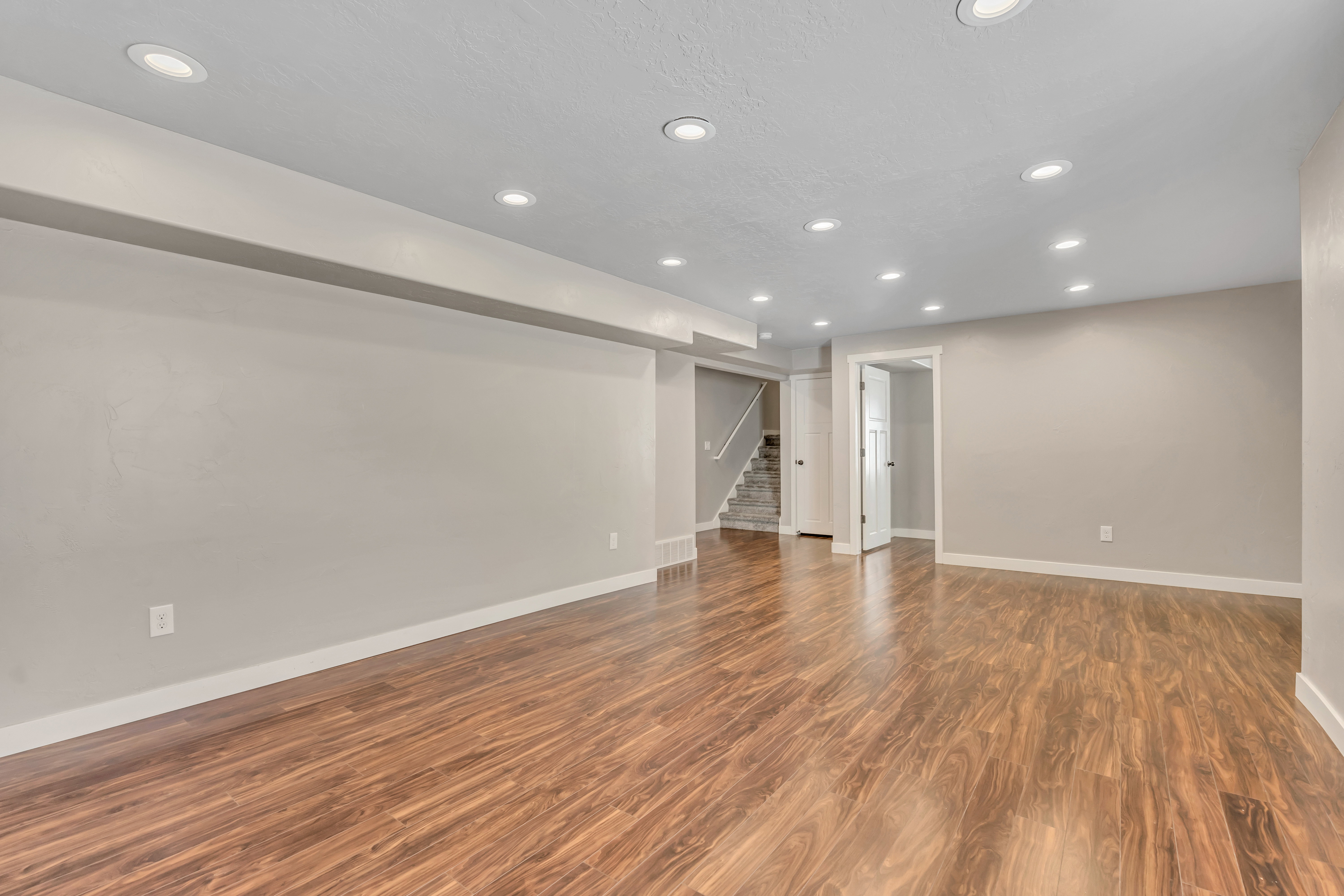 Spacious interior room featuring wood-finish flooring, recessed lighting, and light-toned walls