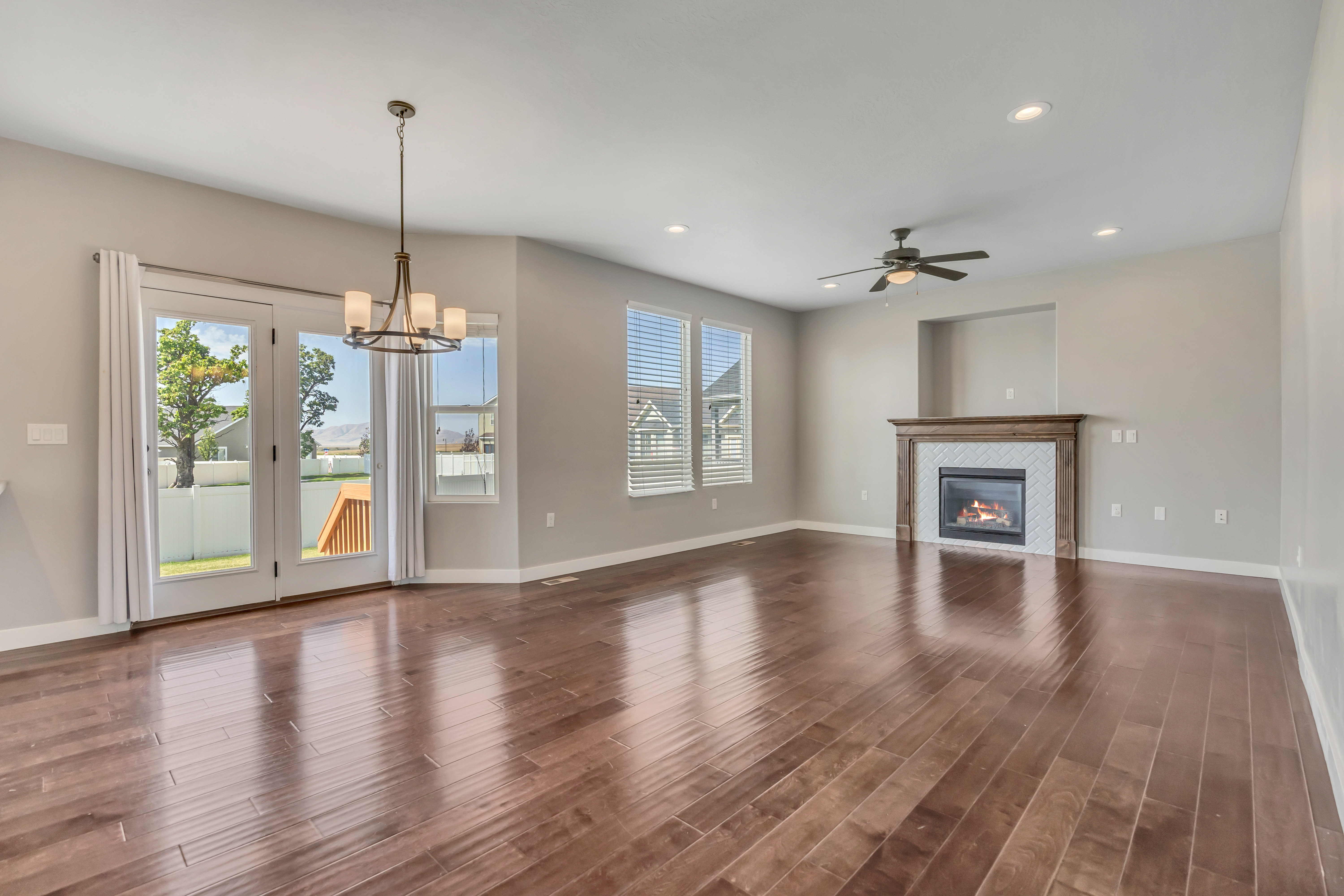 Spacious living area featuring rich wood-finish flooring, a contemporary ceiling fan, and recessed lighting