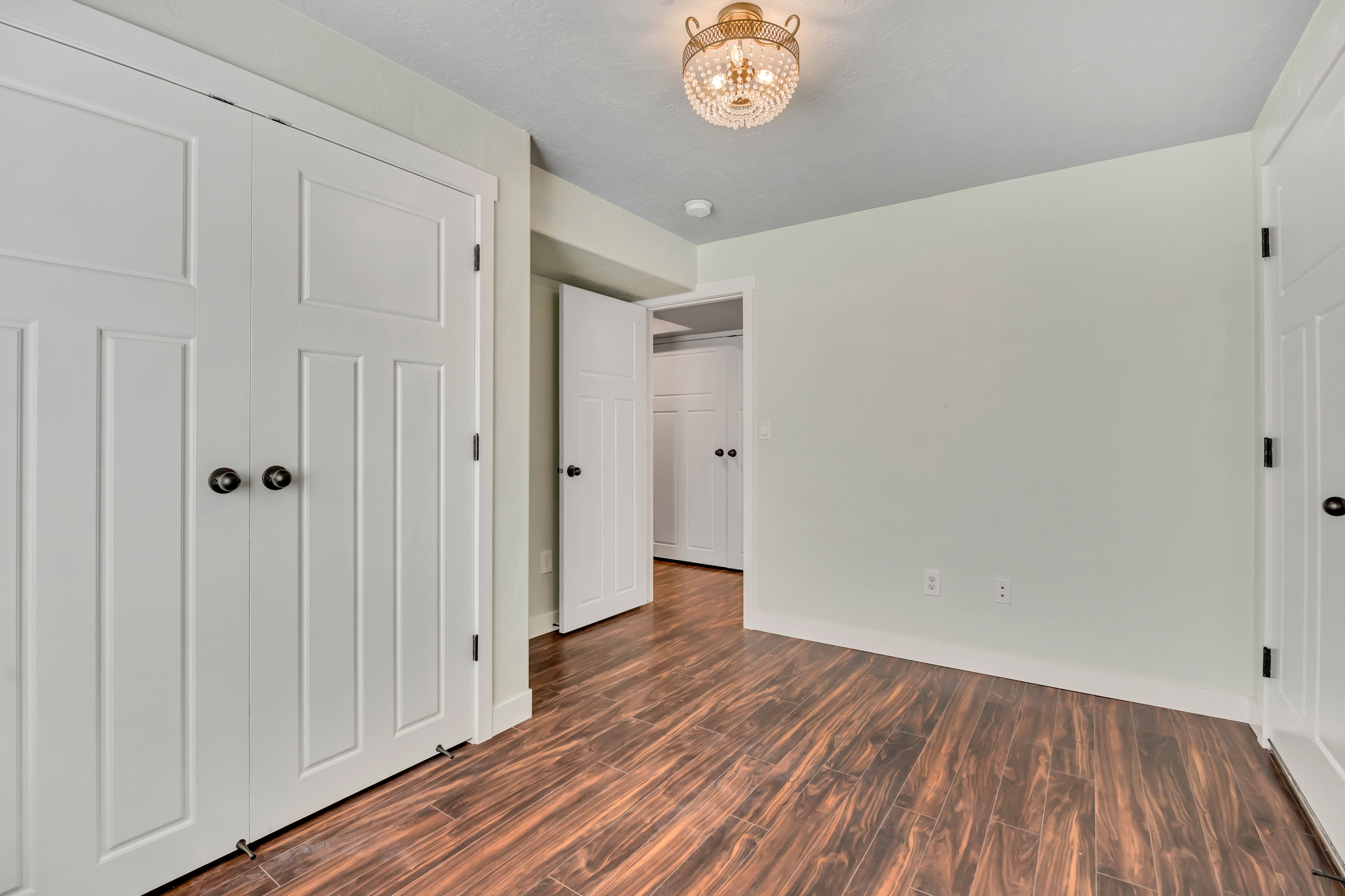 Bedroom featuring wood-finish flooring, white paneled doors, and a decorative semi-flush mount ceiling fixture