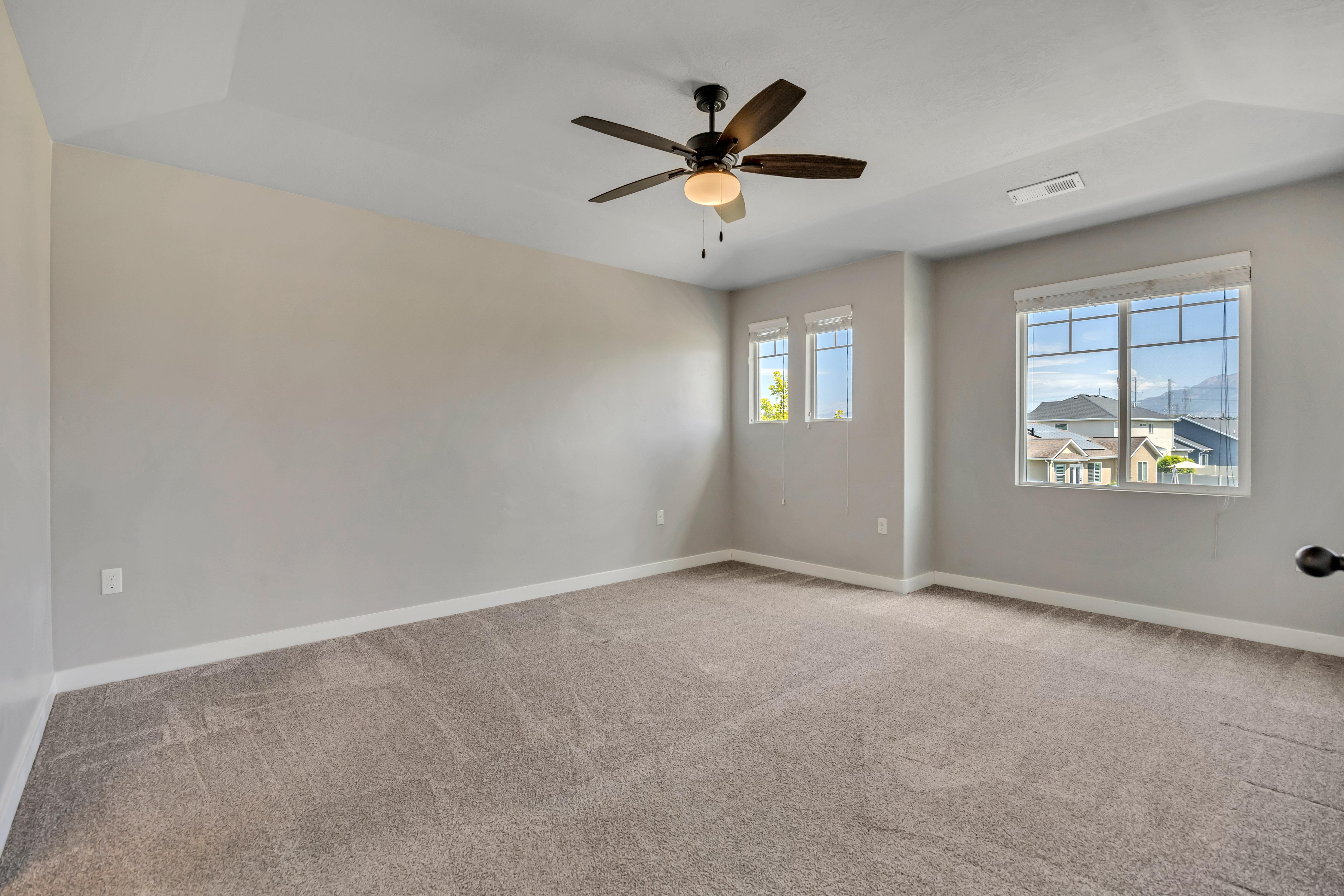 Spacious room featuring neutral carpeting, light-toned walls, and a tray ceiling