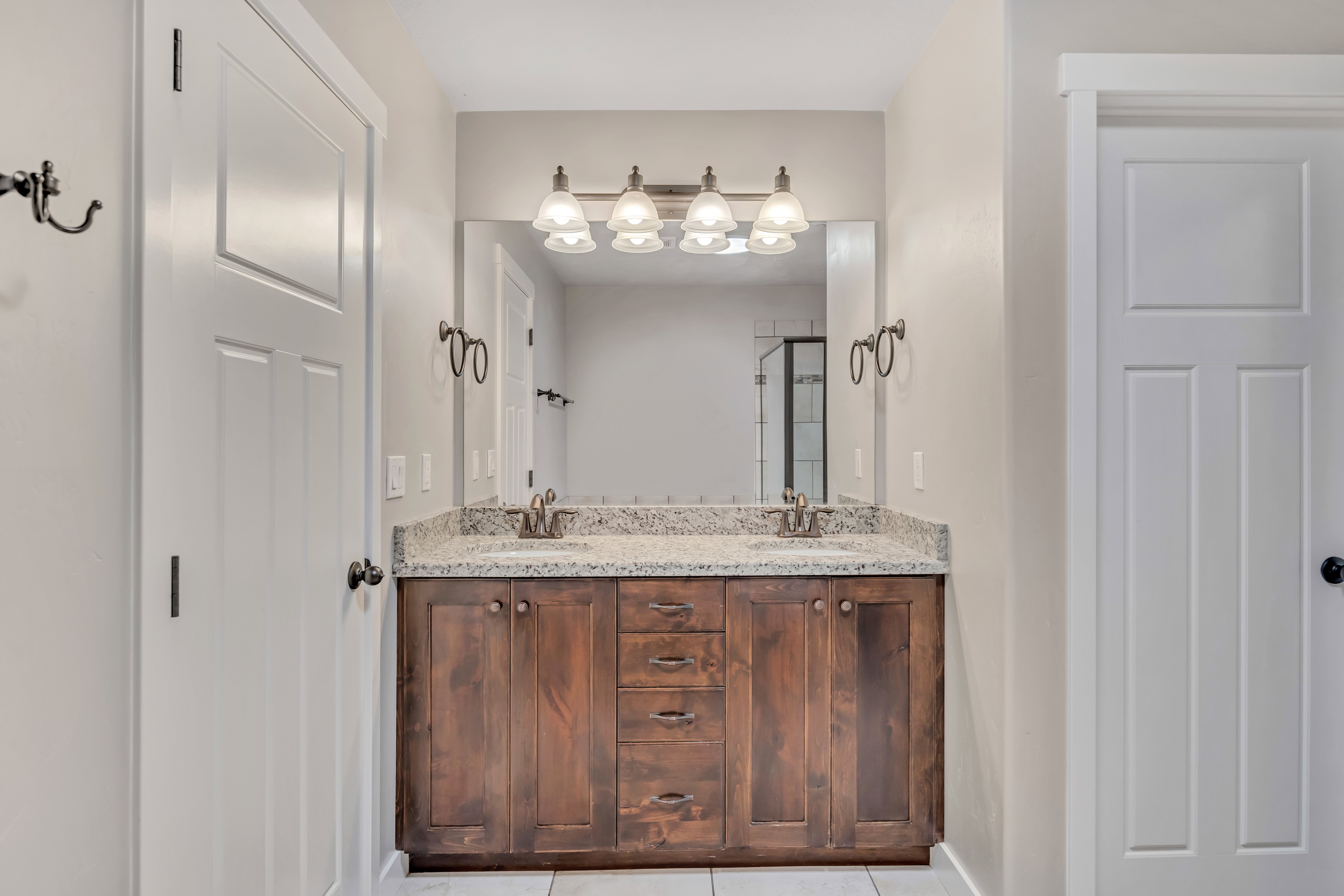 Double vanity featuring a granite countertop, dual undermount sinks, and dark wood cabinetry with brushed nickel hardware