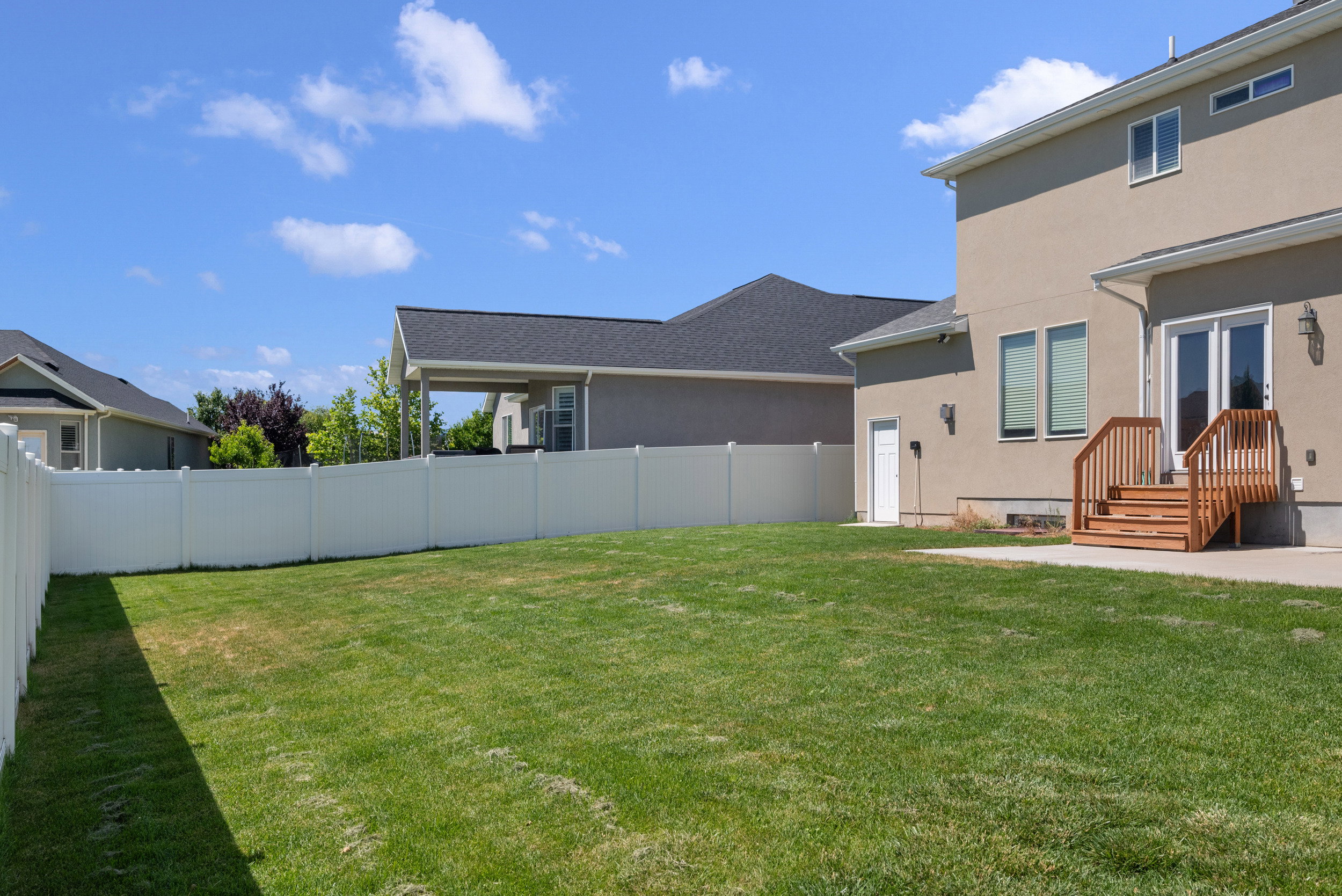 Expansive green lawn with a white vinyl fence