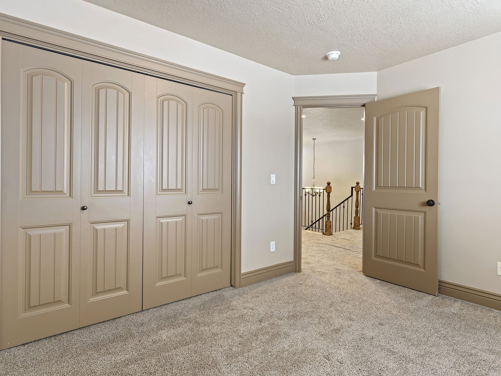 Neutral-toned paneled bifold closet doors with dark hardware, complemented by matching trim and baseboards