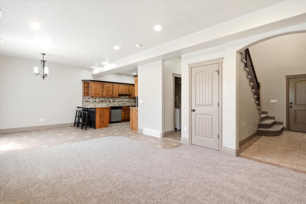 Spacious open-concept area featuring light-toned carpeting and tile flooring