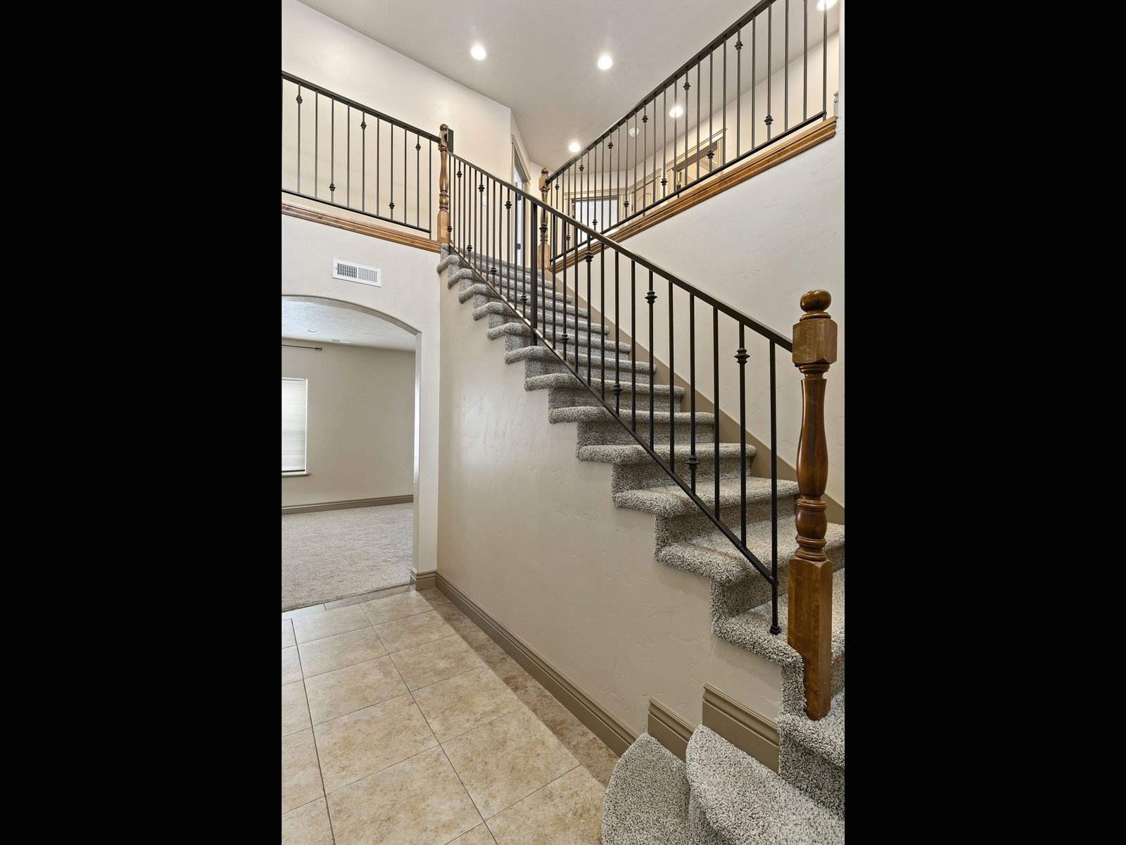 Two-story entryway featuring a carpeted staircase with wrought iron balusters and a wood handrail
