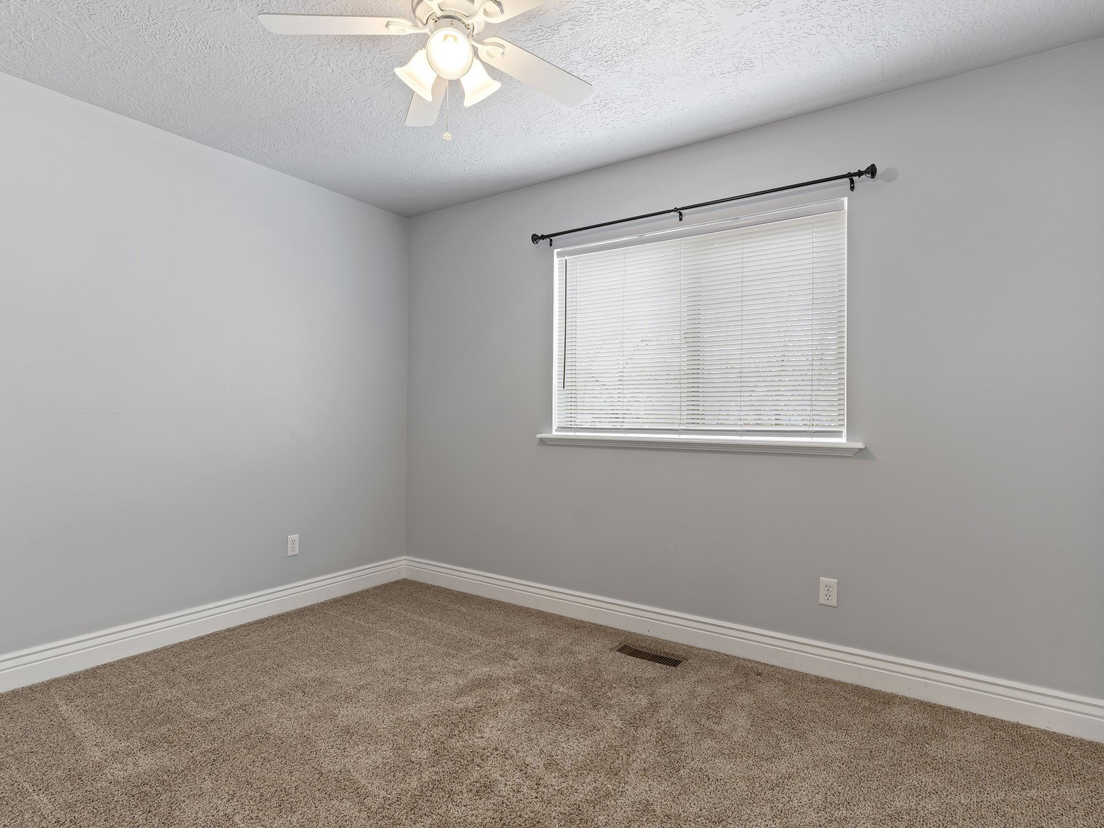 Carpeted room featuring a ceiling fan with integrated lighting, a window with blinds, and white baseboards