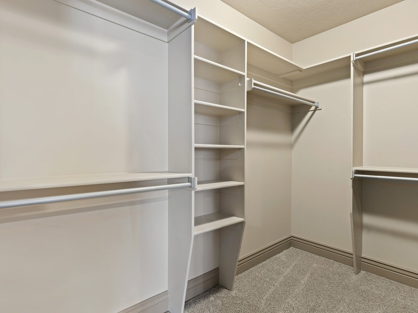 Integrated closet organization system featuring multiple hanging rods, shelving, and corner storage