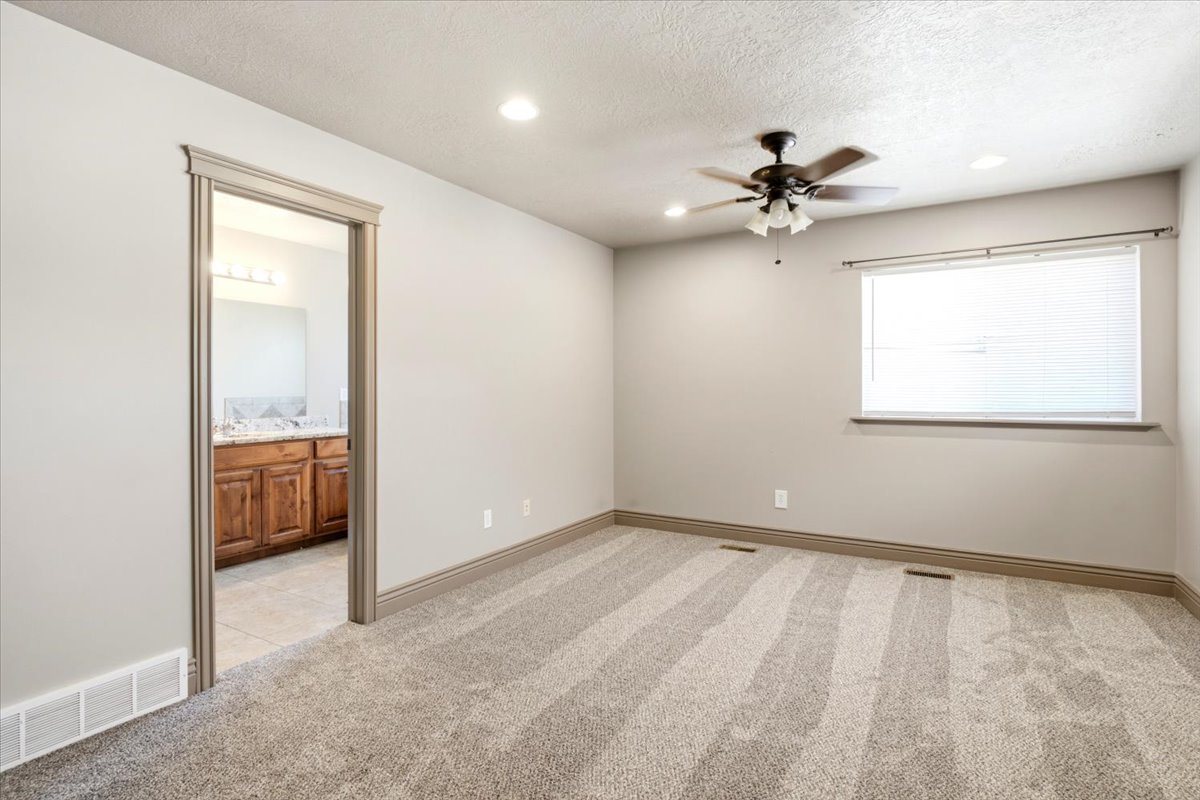 Neutral-toned bedroom featuring wall-to-wall carpeting, recessed lighting, and a ceiling fan