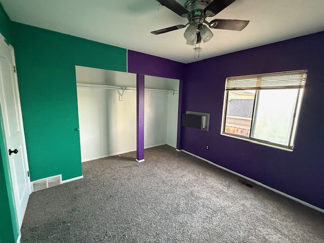 Room featuring two tone wall colors, a ceiling fan, a window with blinds, and built-in closet spaces