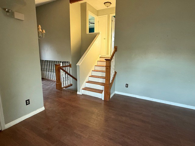 Staircase with wood-finish handrail and balusters, featuring white risers and wood-finish treads
