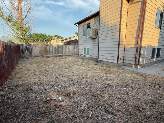Expansive backyard area featuring a wood fence perimeter and a raised garden bed
