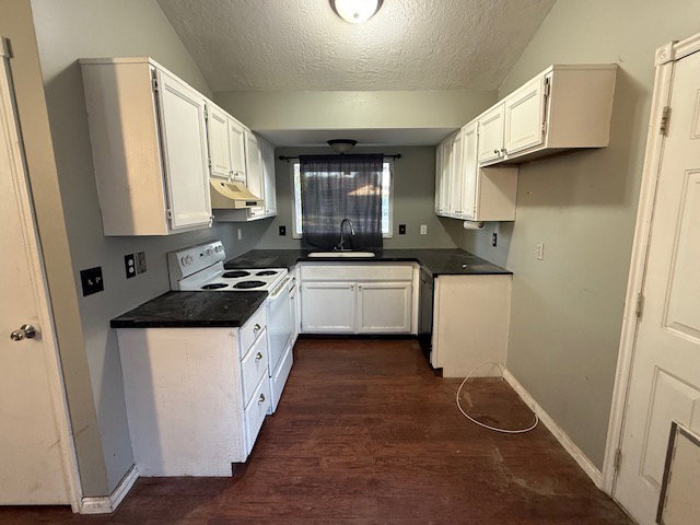 U-shaped kitchen featuring white cabinetry, dark countertops, a white electric range, and a single basin sink with a window above