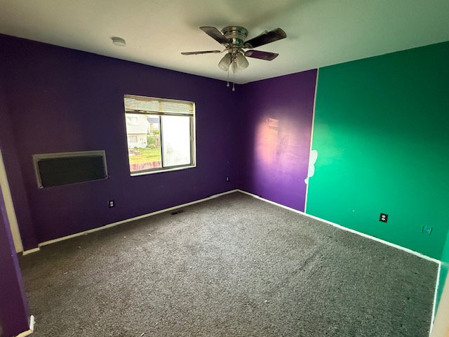 Interior room featuring grey carpeting, a multi-pane window, and a ceiling fan with light fixture