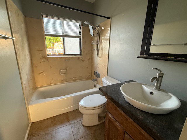 Bathroom featuring a white bathtub, toilet, and a vanity with a vessel sink