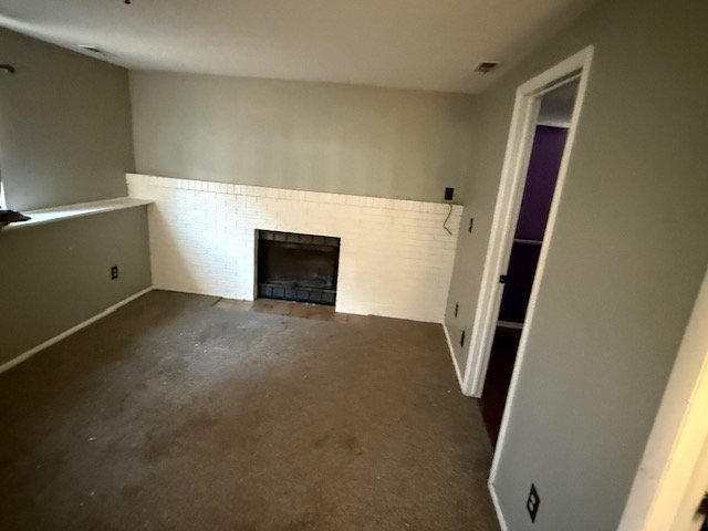 Living space featuring a white brick fireplace with a dark firebox, a built-in ledge, and neutral-toned wall paint