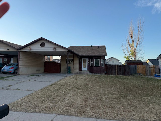 Exterior featuring an attached carport, front yard, and a fenced side yard