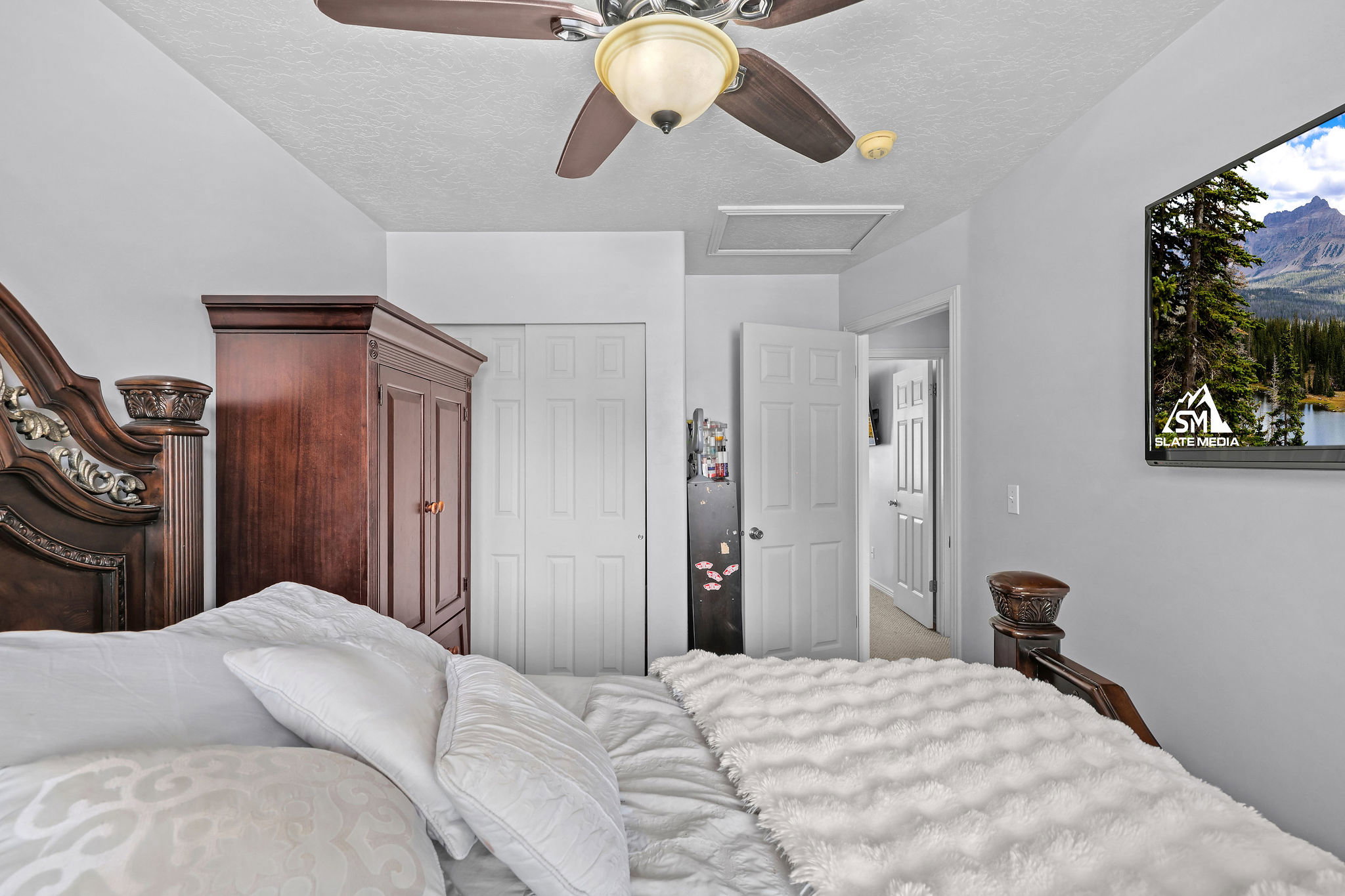 Bedroom with white walls and textured ceiling featuring a ceiling fan with integrated lighting
