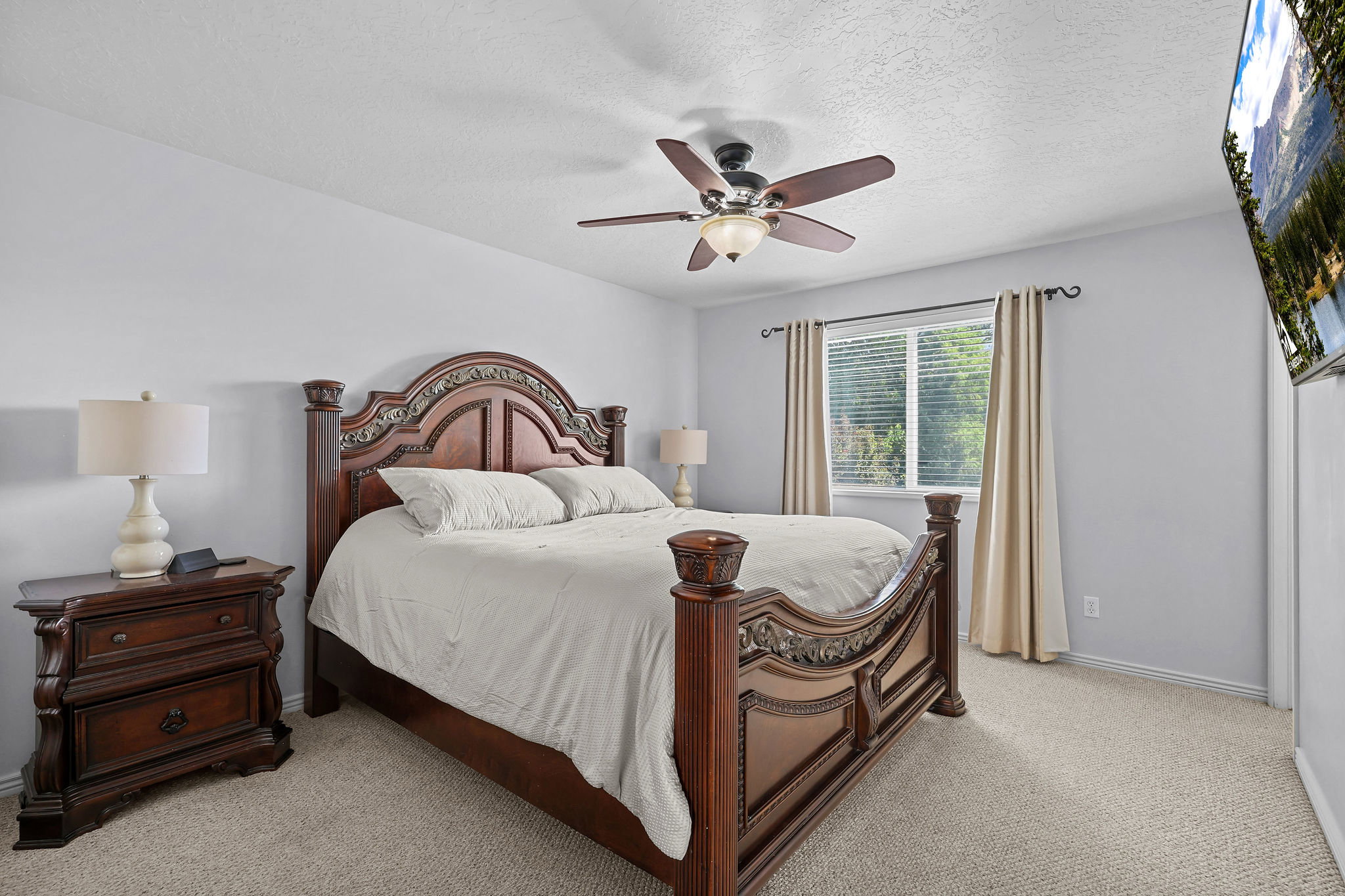 Carpeted bedroom with a single window, a ceiling fan with integrated lighting, and light gray walls