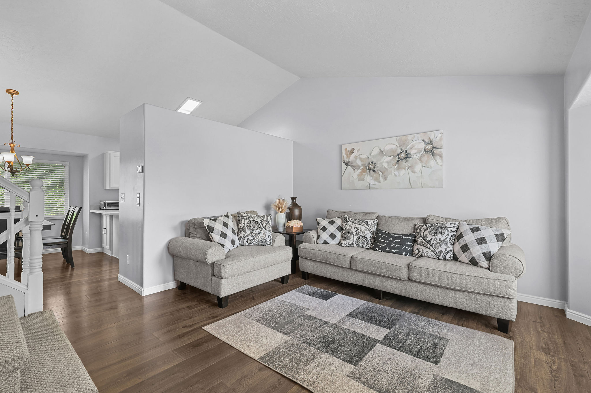 Living area featuring vaulted ceilings, wood-finish flooring, and a neutral color palette