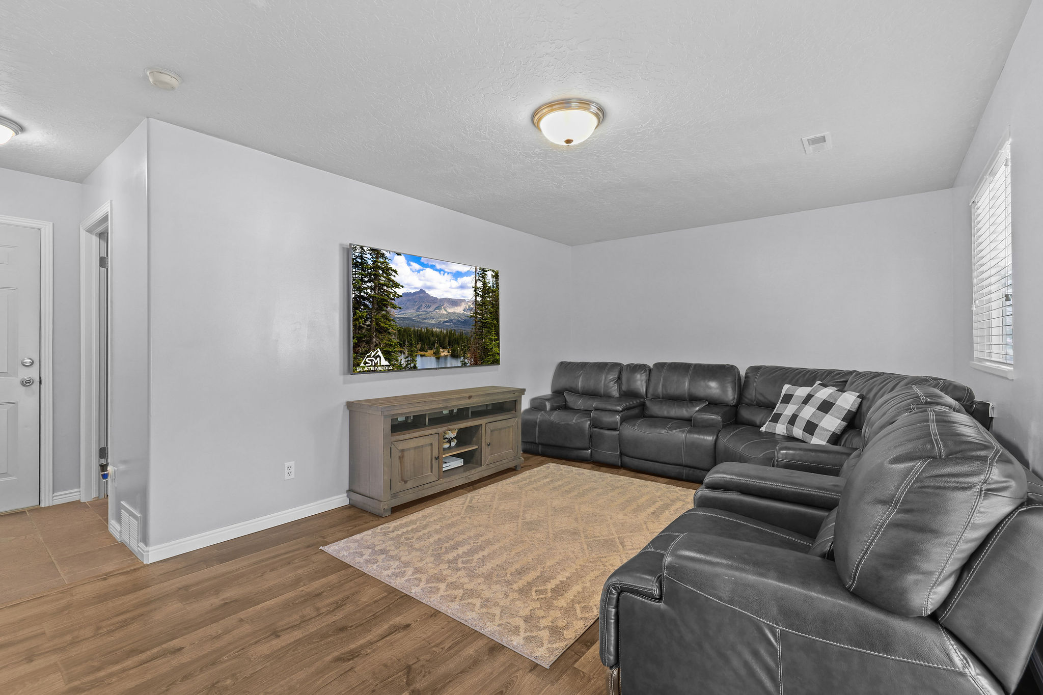 Spacious living area featuring wood-finish flooring, light gray walls, and recessed lighting