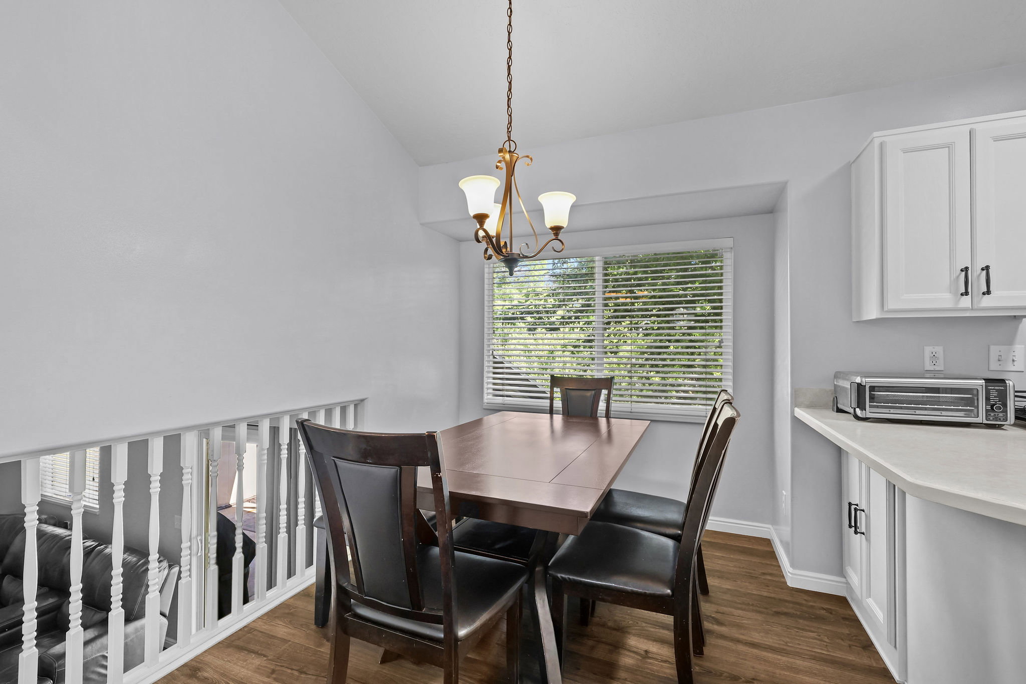 Dining area featuring a contemporary chandelier, wood-finish flooring, and a large window with blinds