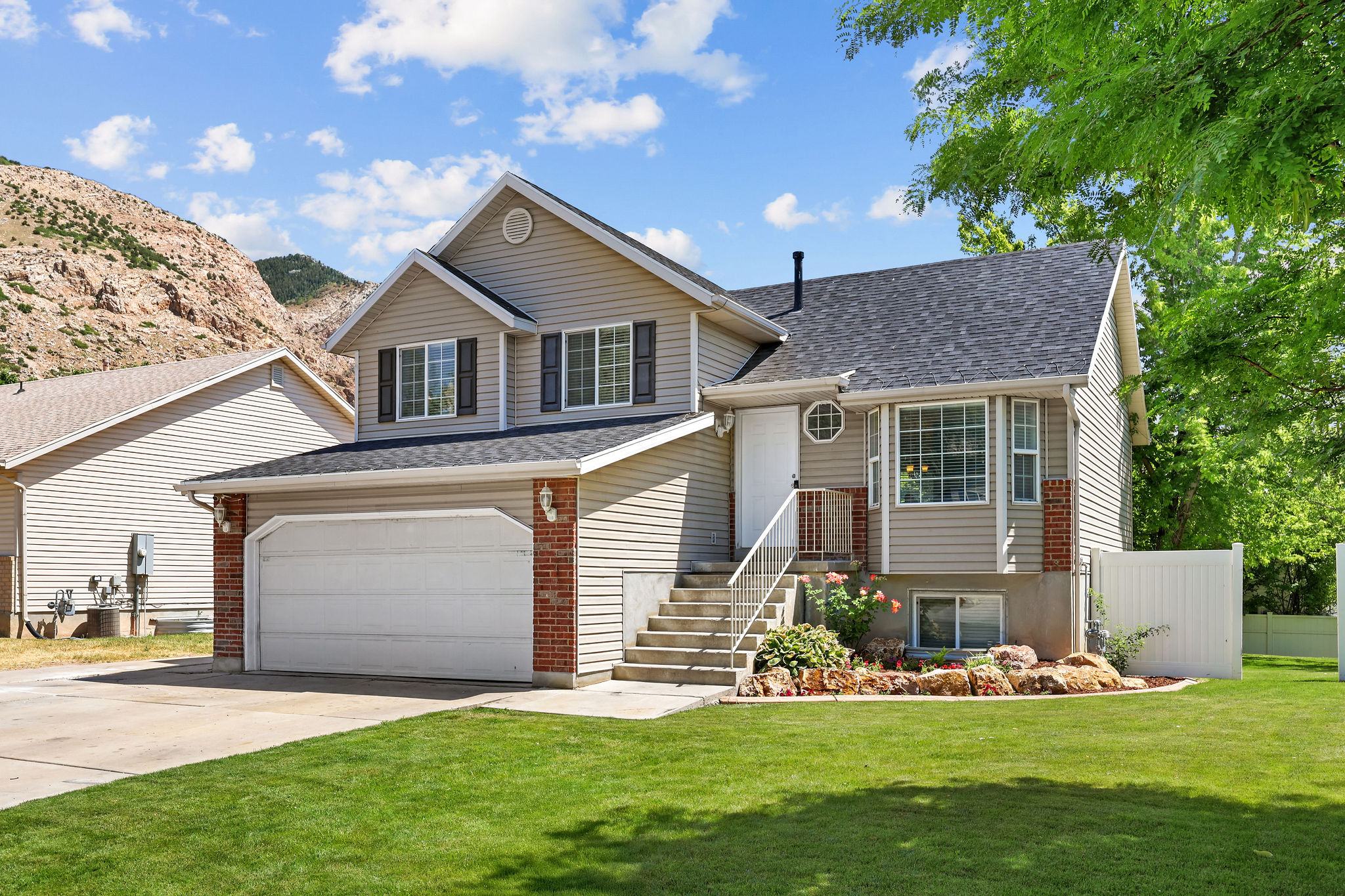 Two-story siding exterior featuring a two-car garage, brick accents, and a front entry staircase