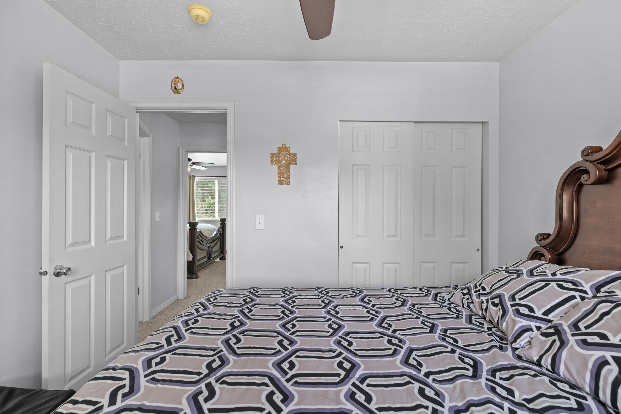 Bedroom featuring light gray walls, wood-finish ceiling fan, and sliding panel closet doors